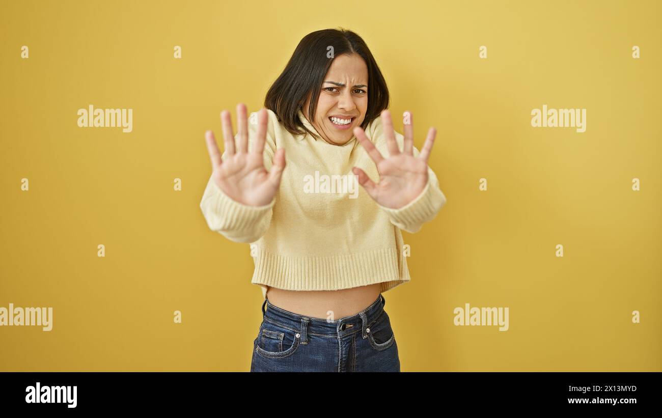 Young hispanic woman with negative gesture against a yellow isolated ...