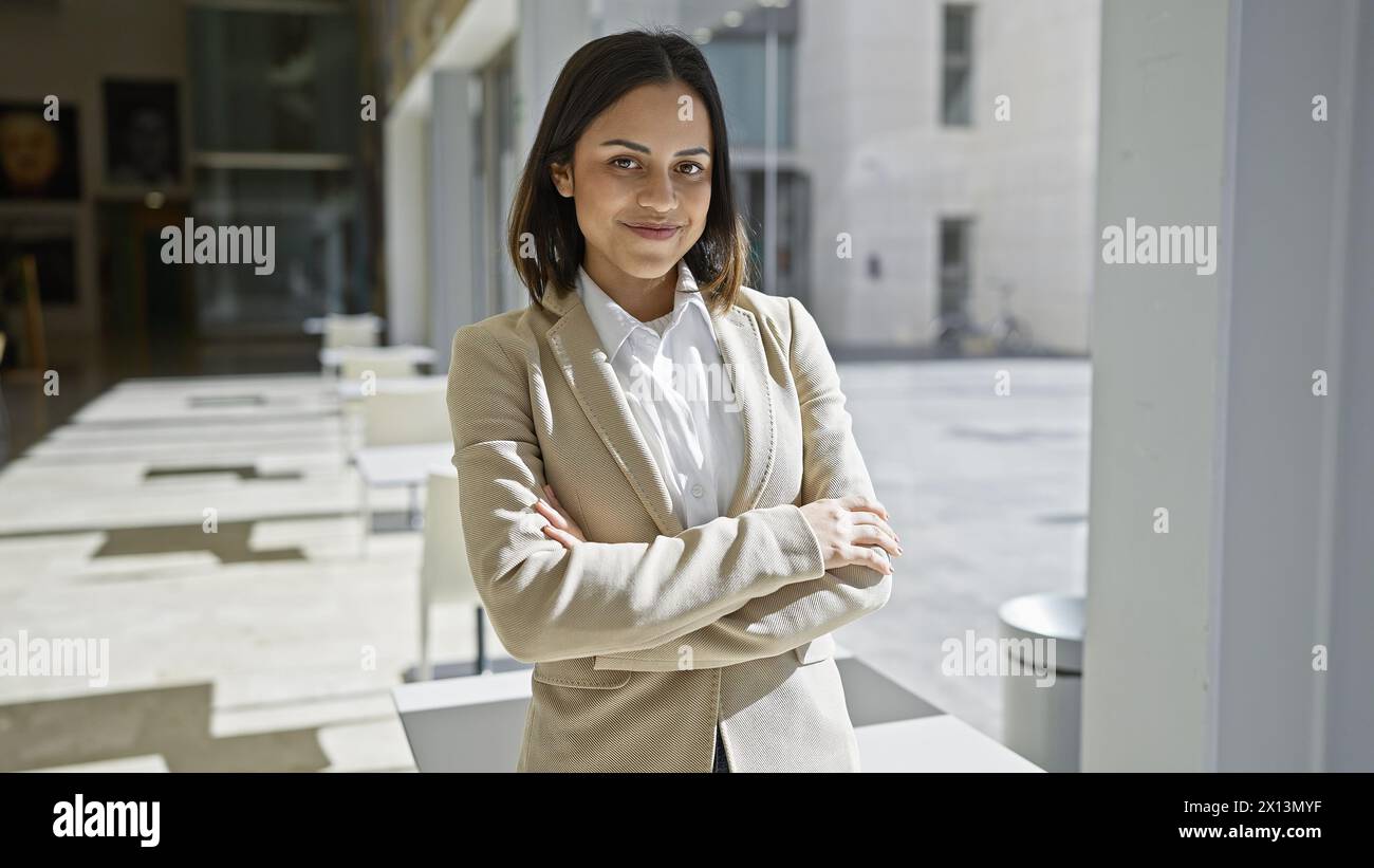 Confident young hispanic businesswoman stands in a modern building ...