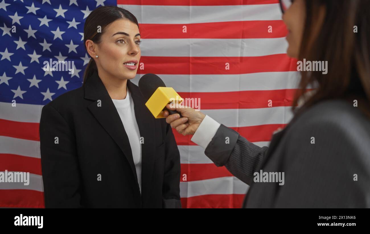 Professional woman interviewed by journalist in room with american flag backdrop. Stock Photo