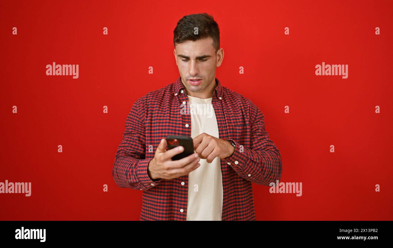 Young hispanic man using smartphone over isolated red background Stock Photo