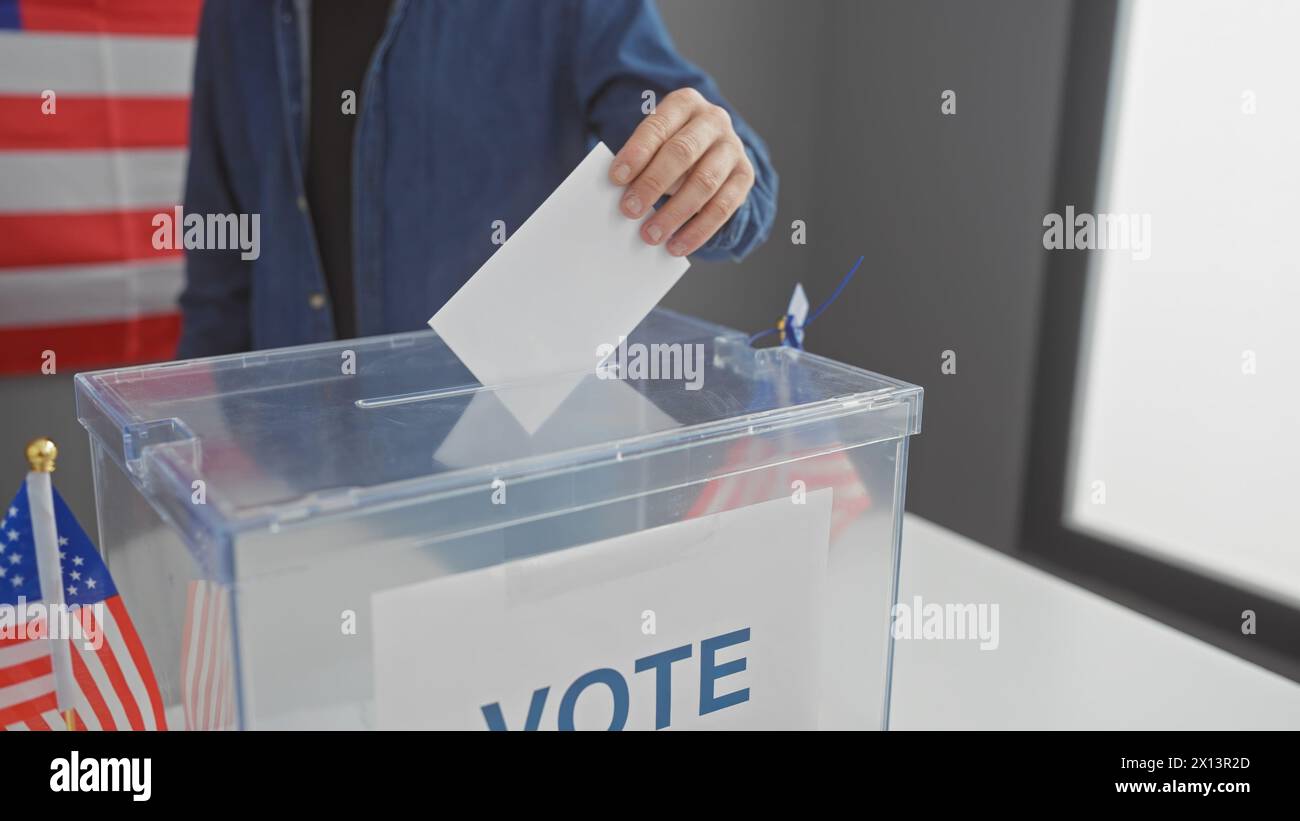 Young man casting ballot at american voting center, flag in background Stock Photo