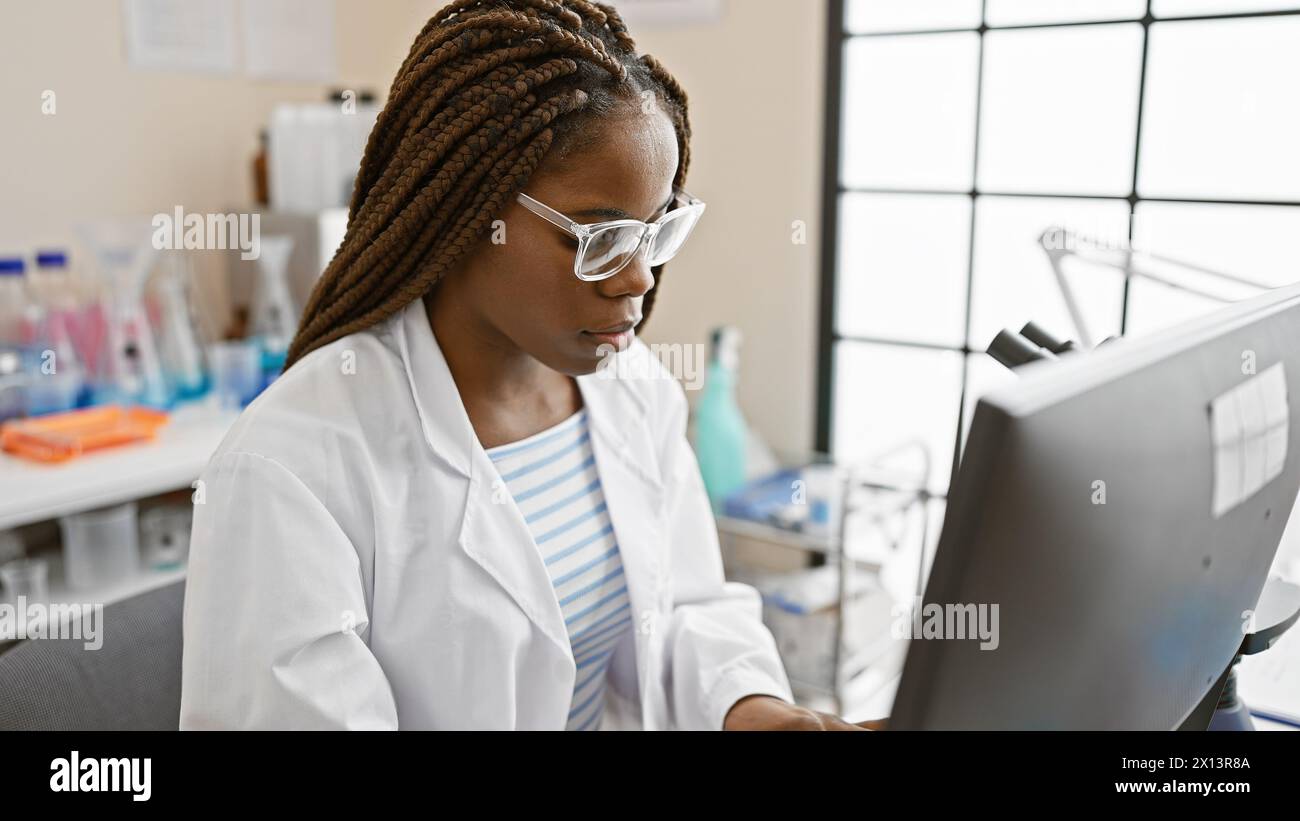 A focused african american woman with braids working in a laboratory ...
