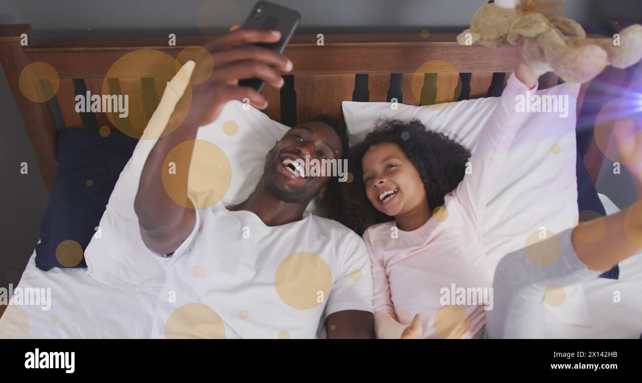 Image of light spots over african american man and his daughter taking selfies Stock Photo