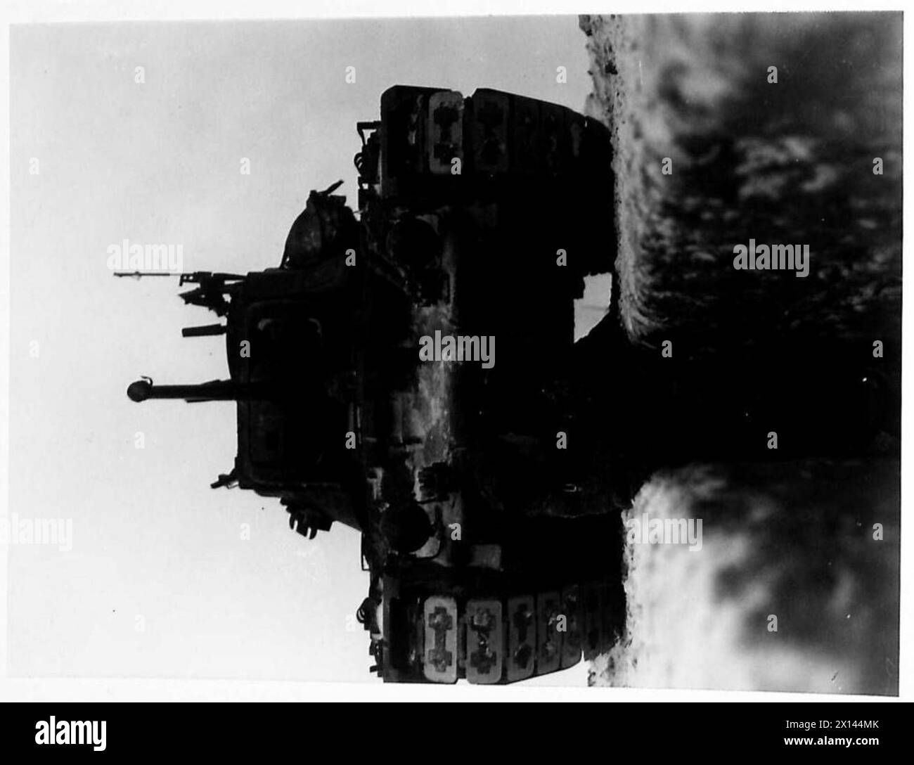 UNDER A TANK - A heavy tank passes over a trench occupied by troops ...