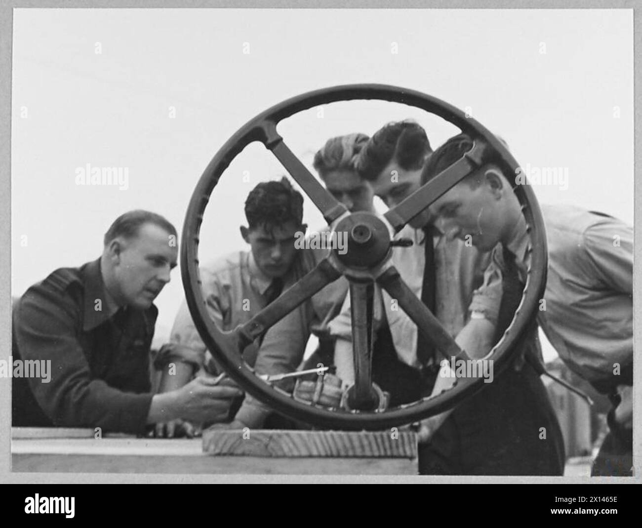 'CIVVY STREET COURSE' IN R.A.F. PATHFINDER GROUP - 16004 Picture issued 1945 shows - View through car steering wheel used for instruction of E.V.T. pupils interested in taking up motor mechanics on leaving the service. Instruction (left) is ex-garage owner Flight Lieutenant E.E. Fenning [see above] - he was formerly Mosquito pilot Royal Air Force Stock Photo