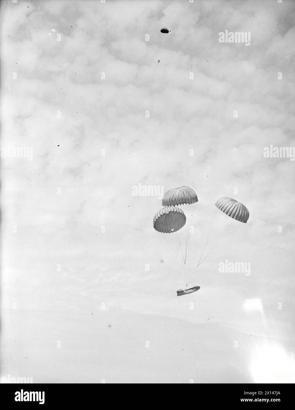 LIFEBOAT DROPPED FROM AIR. 13 JULY 1945, LEE-ON-SOLENT. THE DEMONSTRATION DROP OF THE NAVY'S AIRBORNE LIFEBOAT, 17 FT, 9 INS LONG, WHEN IT WAS DROPPED BY PARACHUTE TO AN AIR CREW WHO WERE SUPPOSED TO HAVE FORCED LANDED INTO THE SEA. THE LIFEBOAT, SELF-RIGHTING, AND SELF-BALING IS EQUIPPED WITH SAILS AND AN OUTBOARD ENGINE WHICH GIVES IT A RANGE OF 120 MILES AT 4 KNOTS. - The lifeboat held by three parachutes, dropping from the Fairey Barracuda Stock Photo