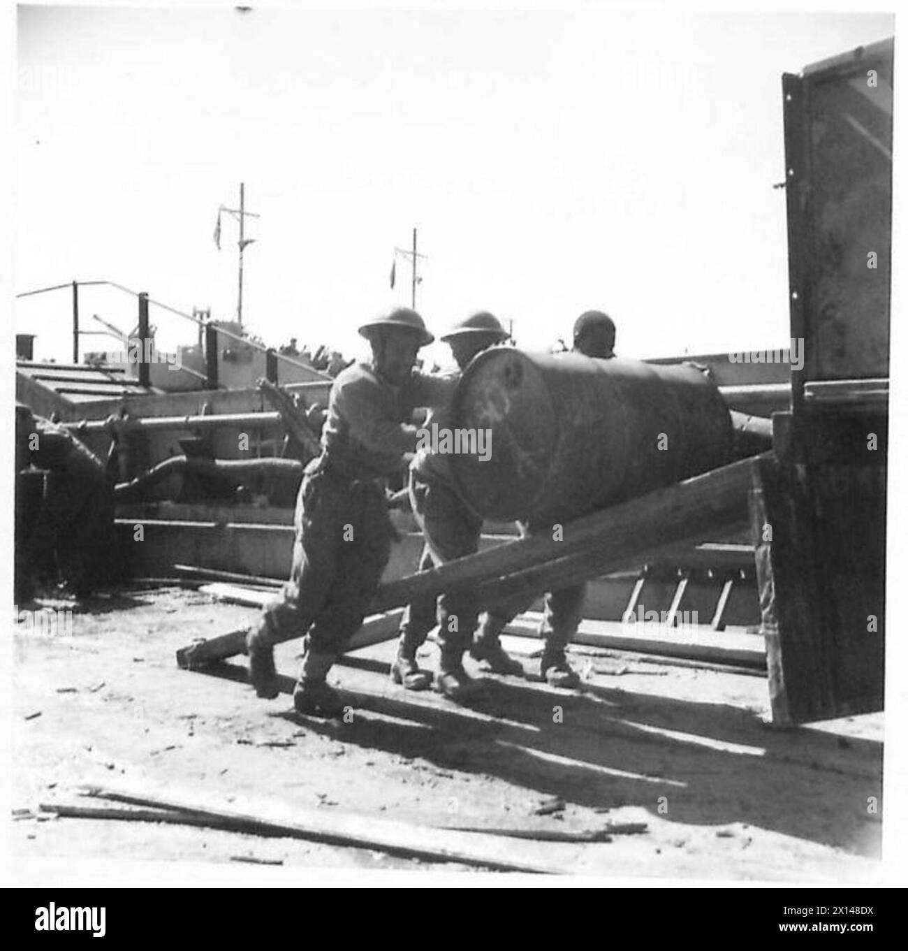 FIFTH ARMY : ANZIO BRIDGEHEAD.SOUTH AFRICAN COLOURED TROOPS AT ANZIO - SWazi troops loading drums of petrol on to a lorry ehich has been backed on to the landing craft. As they work the men chant a native song British Army Stock Photo