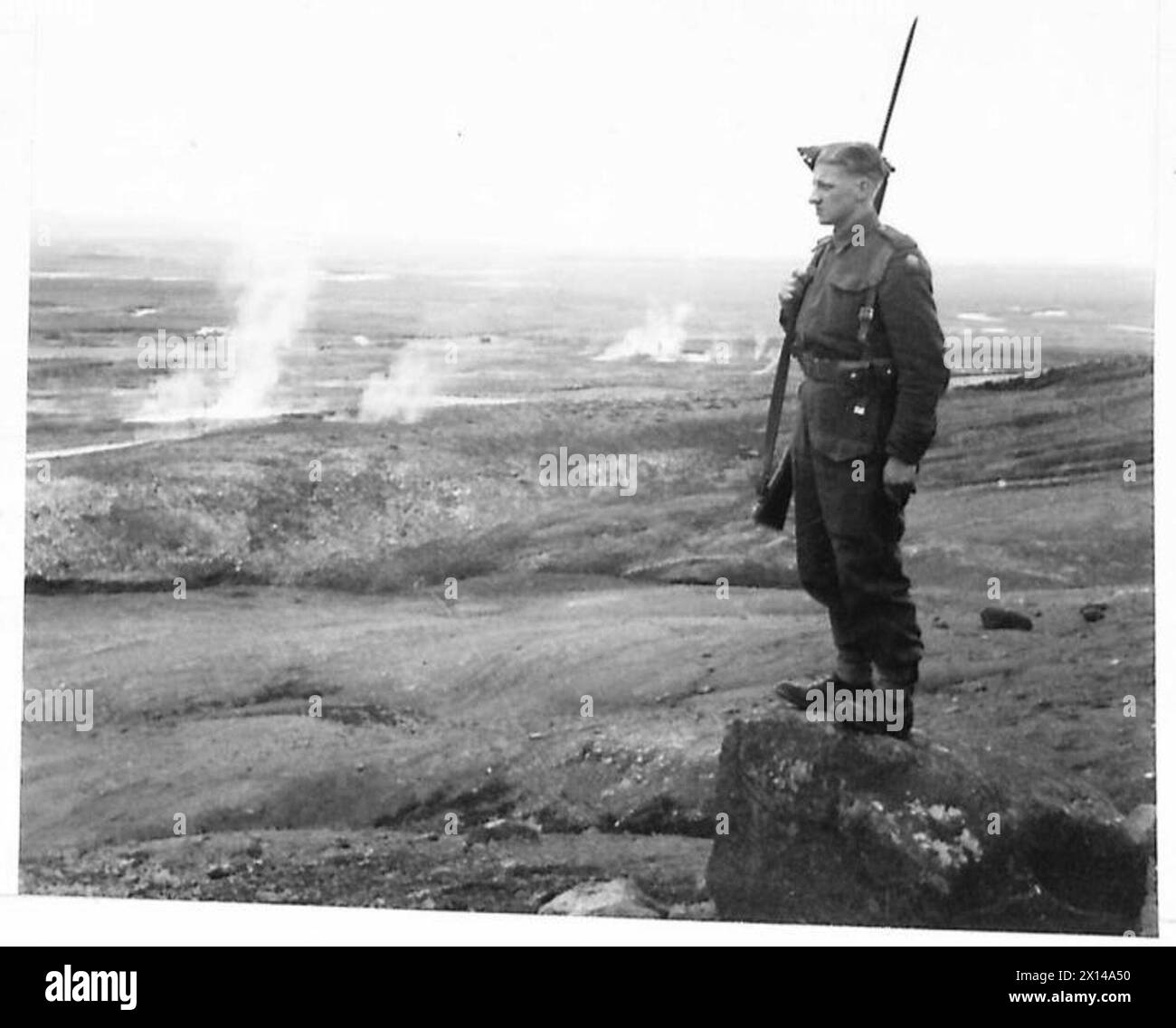 WITH THE BRITISH TROOPS IN ICELAND - A British solider on the lookout in a region of Iceland where there are many hot springs, some of which can be seen in the background, at Geysir British Army Stock Photo
