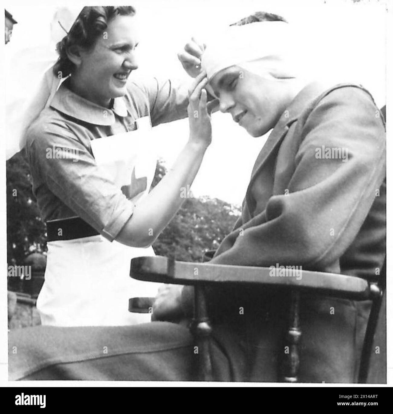 THE BRITISH RED CROSS AND ST. JOHN WAR ORGANISATION - Readjusting the head bandage of Private A. Janes of the Bedfordshire and Hertfordshire Regiment British Army Stock Photo