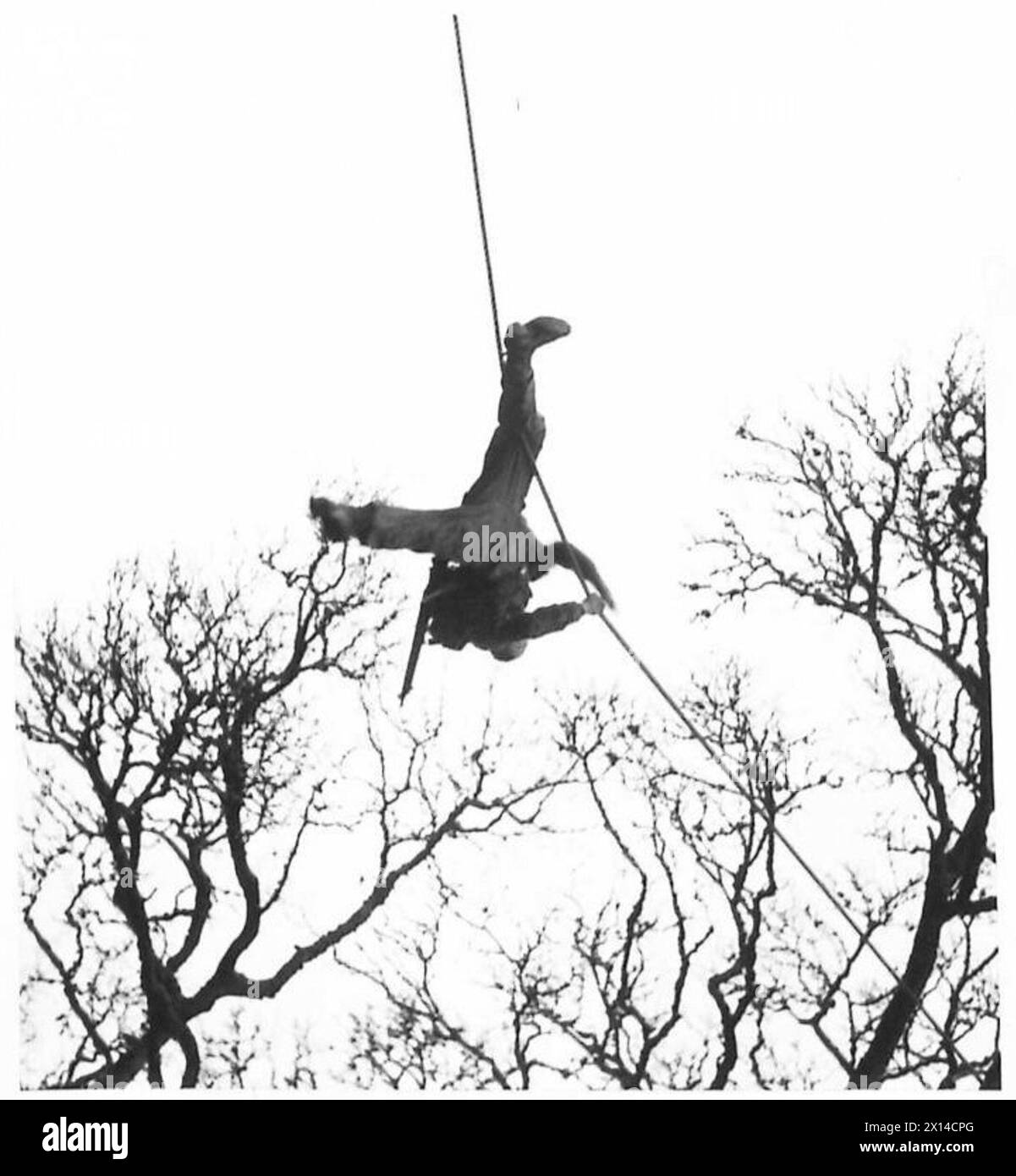 Commandos in training perform rope climbing exercises while observed by ...