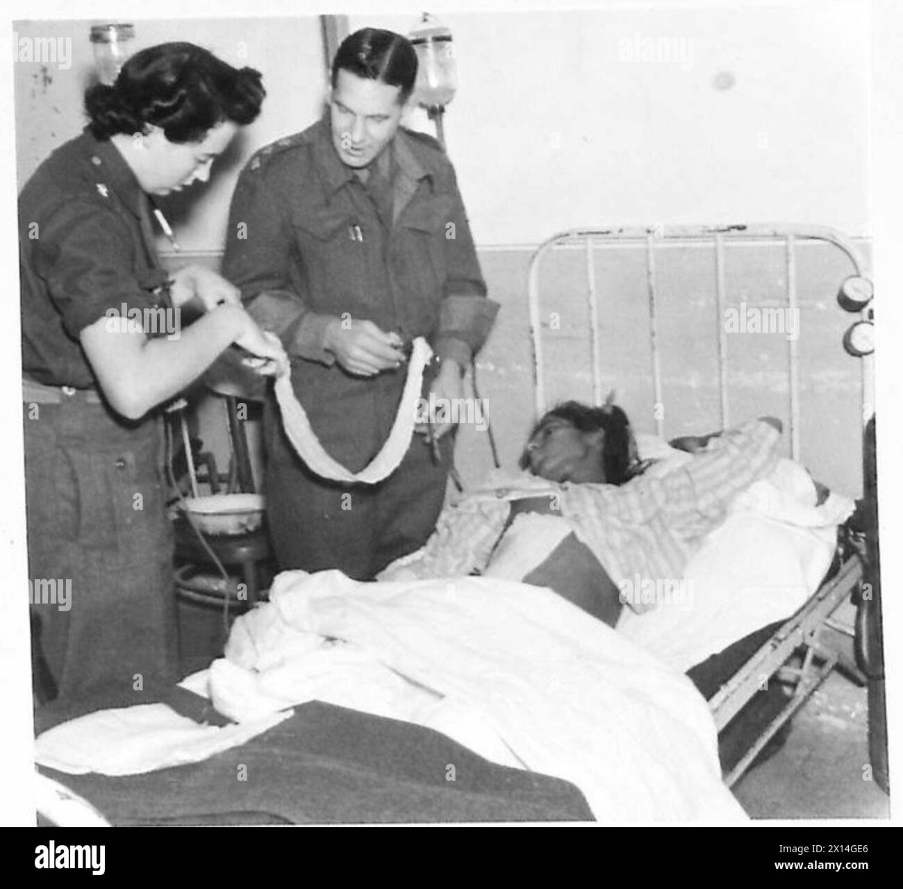 A Ward Doctor assists a front-line nurse in preparing fresh dressings for patients, with dressings changed multiple times a day under the British Eighth Army in Italy. Stock Photo