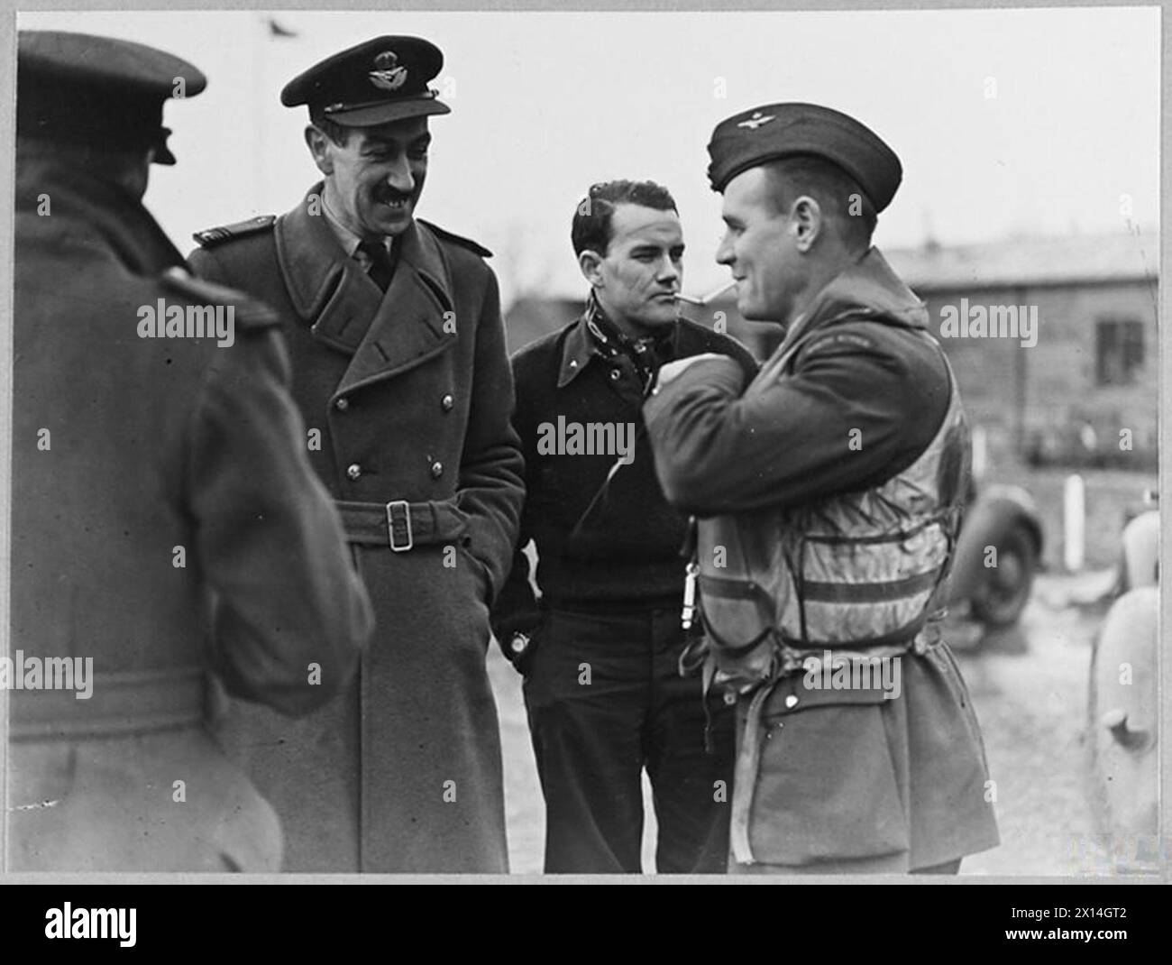 BRITAIN'S ACE FIGHTER PILOT TAKES OVER COMMANDOF A CRACK FIGHTER STATION - 8103 The moment he has been longing for - Group Captain A.G, Malan dons a Mae West before a flight. On the left is the station Intelligence Officer - S/Ldr. de la Torre Royal Air Force Stock Photo