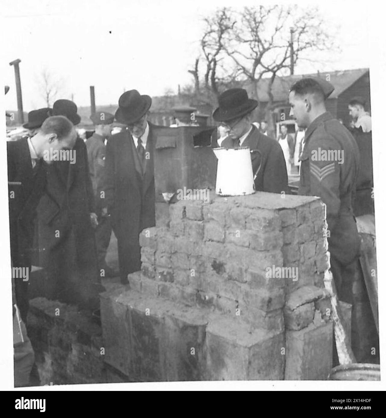 MEMBERS OF PARLIAMENT VISIT TRAINING CENTRE - Old petrol tins, bricks and cement go to make this field kitchen, which MPs are viewing with interest British Army Stock Photo