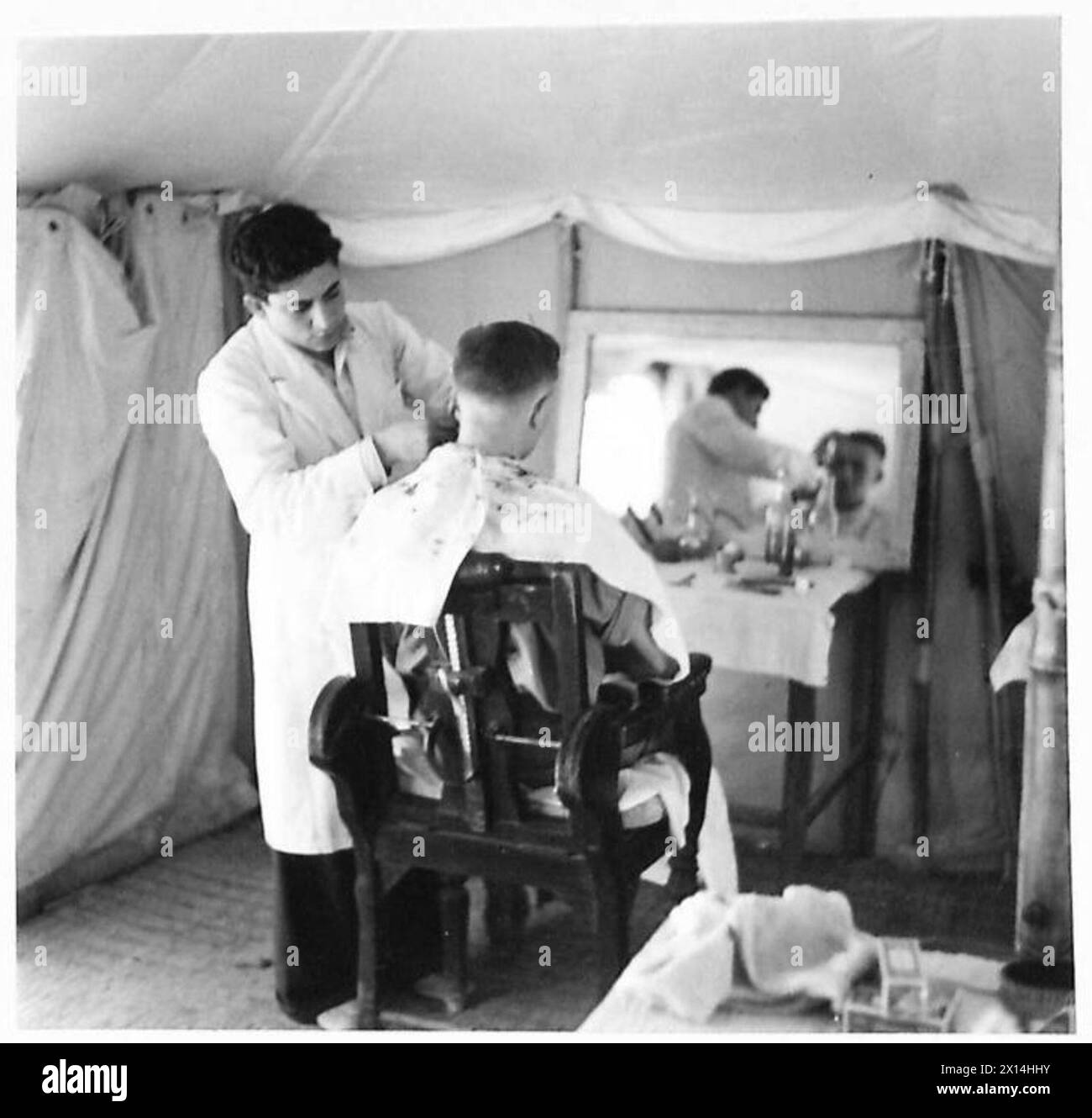 THESE PHOTOGRAPHS WERE TAKEN AT THE REQUEST OF MAJOR RUSTON OF 'PARADE' - A trim-up in the Barber's Shop in the Camp British Army Stock Photo