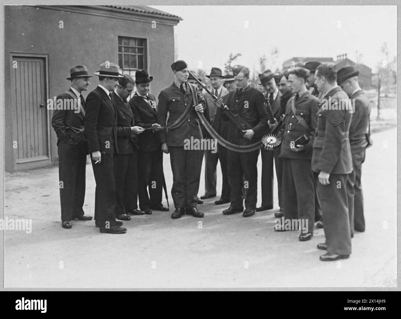 In May 1940, journalists inspect a belt of .303-inch ammunition at ...