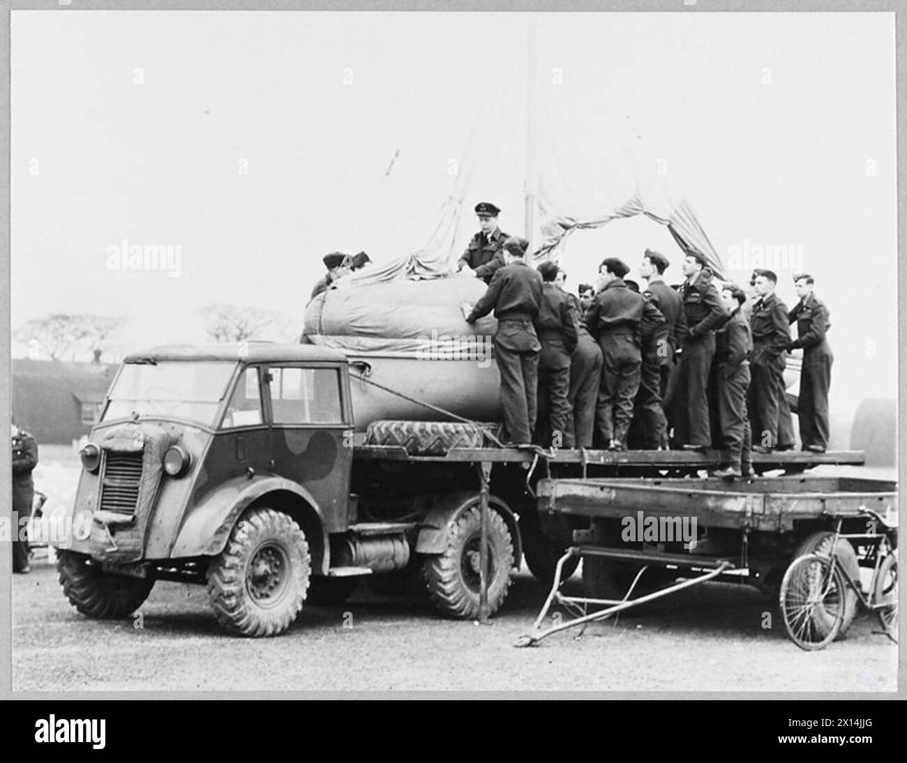 'AIRBORNE LIFEBOAT' DEMONSTRATED TO AIRCREWS - 'The Boat on the Float' is becoming a familiar sight on the airfields of Bomber Command. This strange craft is the airborne lifeboat, the latest appliance for rescuting airmen forced to ditch in the sea. Mounted on a lorry, it is being taken on a tour of Bomber Squadron, so that the men who have to use it may be familiar with it and know how to handle it. An Air/Sea Rescue expert demonstrates how to rig the sails and handle the small motor. The lifeboat is flown to the spot where the airmen are adrift. It is attached to the belly of the aircraft l Stock Photo