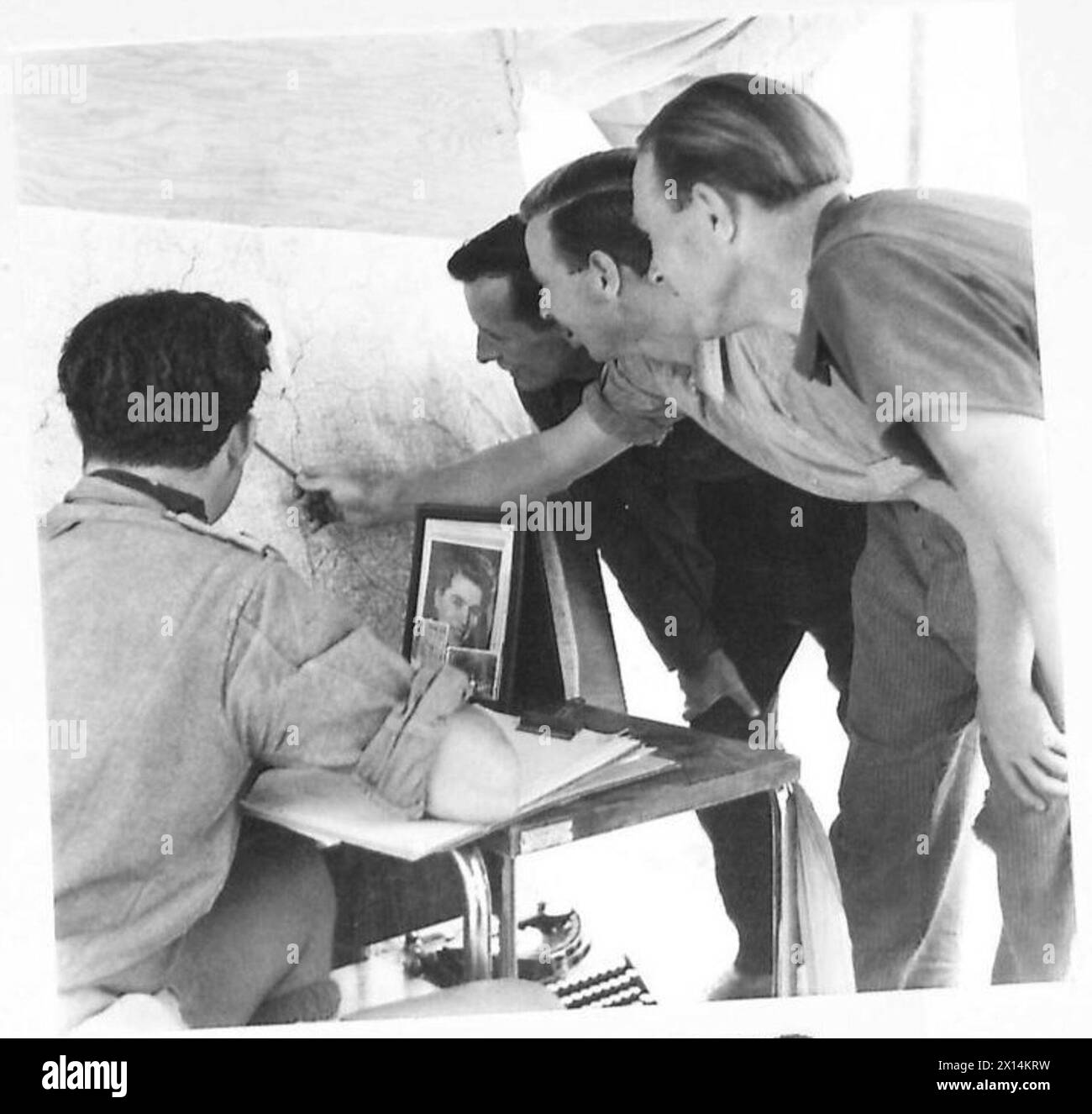 Three escaped British prisoners from the Eighth Army report enemy positions as they approach Allied lines. Stock Photo