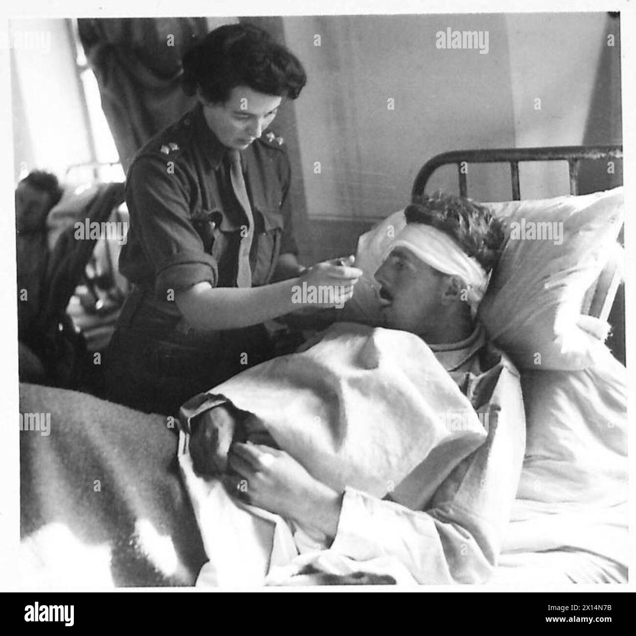 Sister Gibson encourages Private Spinney from Nova Scotia to eat during dinner at a front line post in Italy with the Eighth Army. Stock Photo
