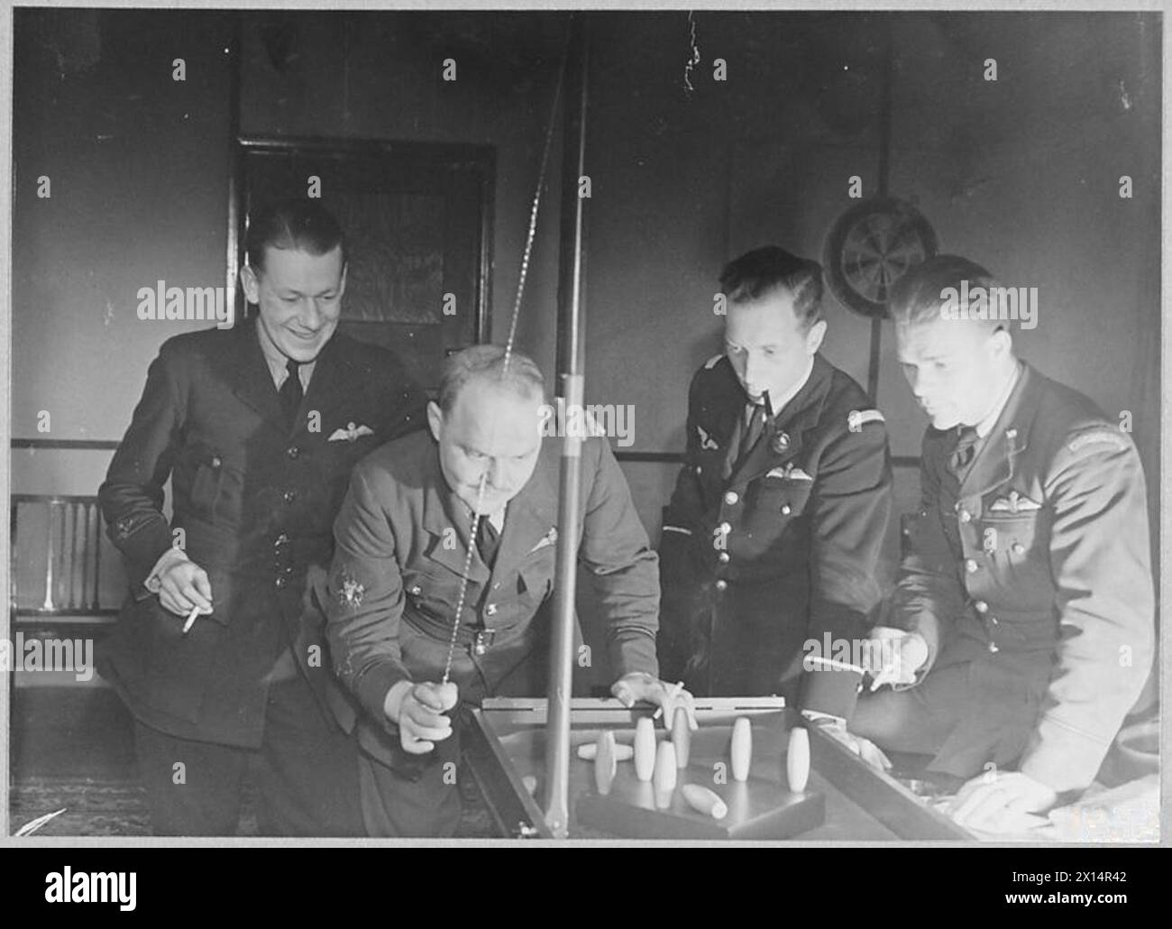 NIGHT FIGHTERS - This night fighter squadron has seven different nationalities among its pilots. Here are four of them playing skittles in the mess. They have one thing in common. They know how to bring them down Royal Air Force Stock Photo