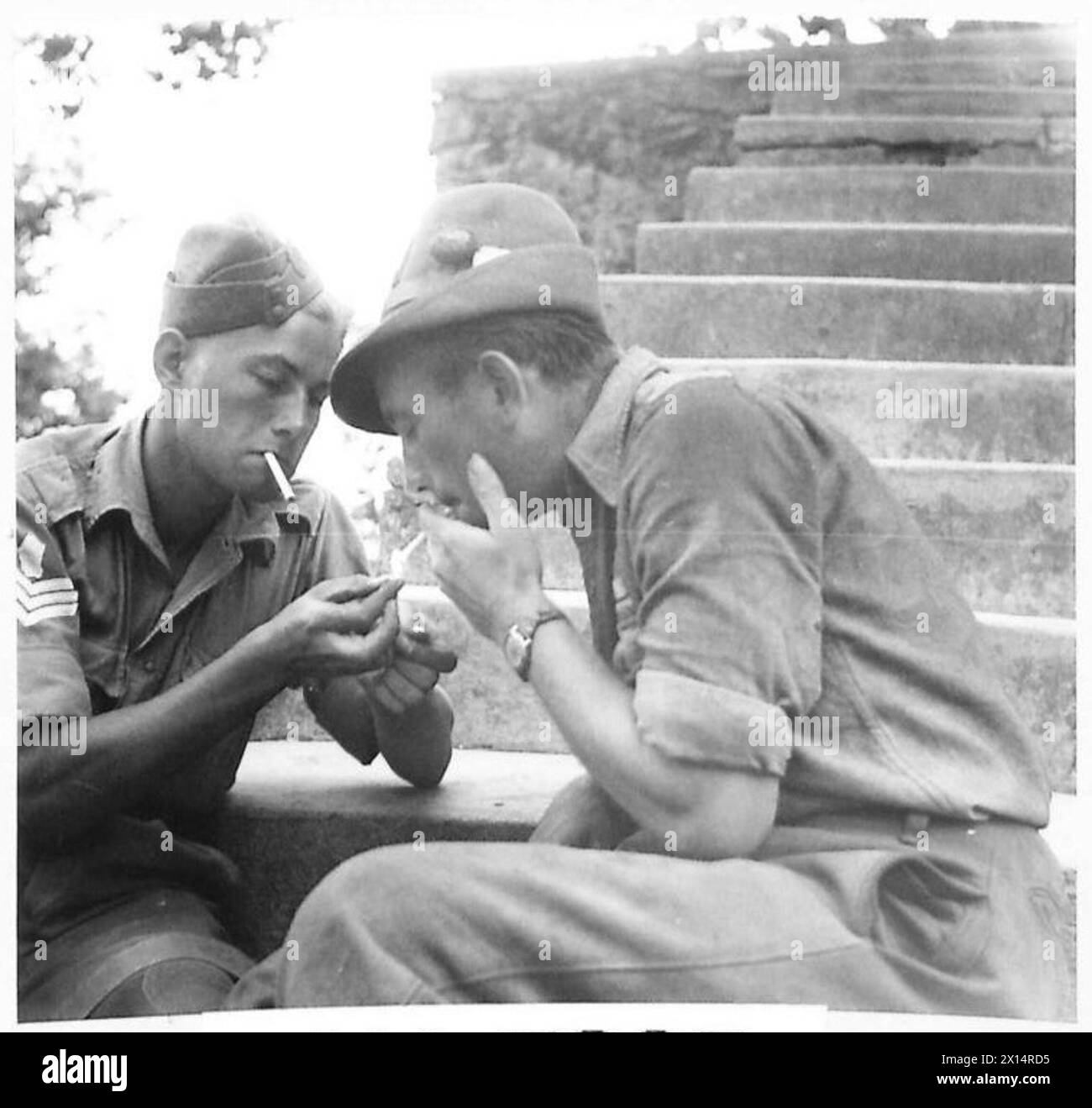 Two NCOs, one English and one Italian, share a smoke while serving alongside each other on the Eighth Army front during the invasion of Italy. Stock Photo
