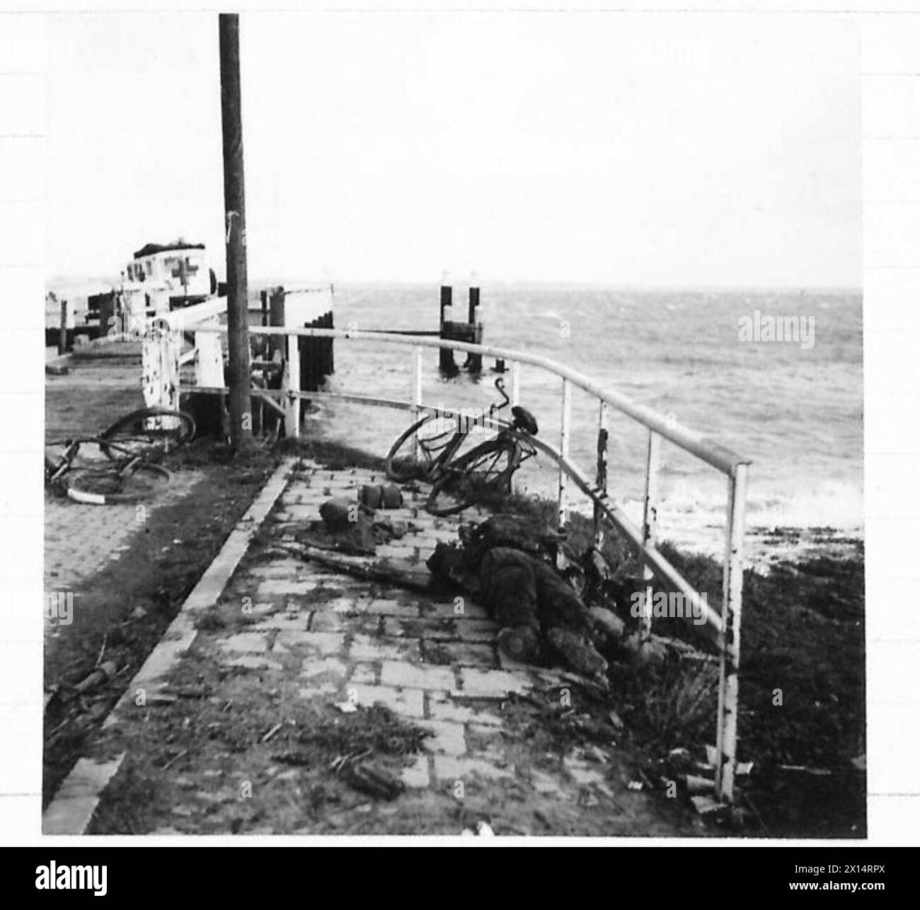 BRITISH PUSH NORTH OF MARK, HOLLAND - A dead German on the quay: he was a tough paratrooper. His rifle and cycle lie beside him. With others, he was caught by our artillery attempting to make a get-away British Army, 21st Army Group Stock Photo