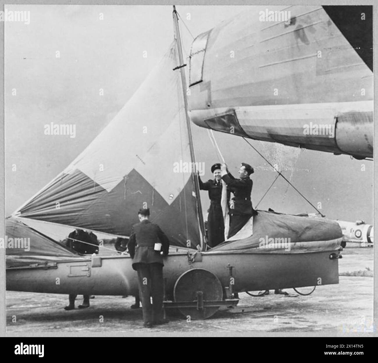 R.A.F'S AIRBORNE LIFEBOATS - The Airborne lifeboat, dropped by parachute, is a new device of Air/Sea Rescue. The lifeboat, made of wood with two buoyancy chambers, 27ft. in length, complete with sails, has two motors beside rocket life-lines which operate when the lifeboat alights on the sea. Picture (issued 1944) shows - Airmen erecting the airborne lifeboat Royal Air Force Stock Photo