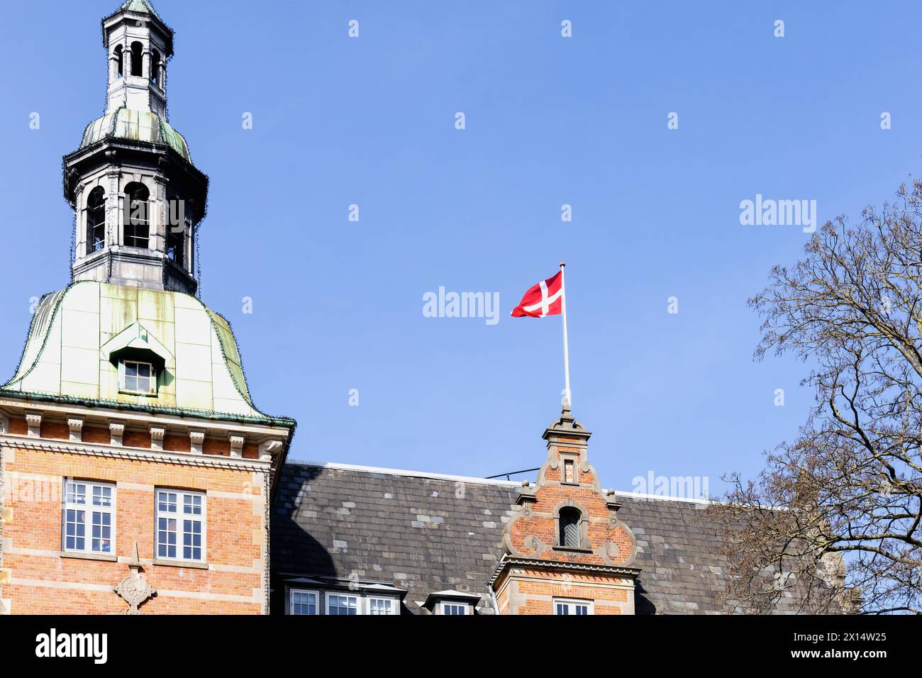 Danish flag on the roof of a building against a blue sky. Stock Photo
