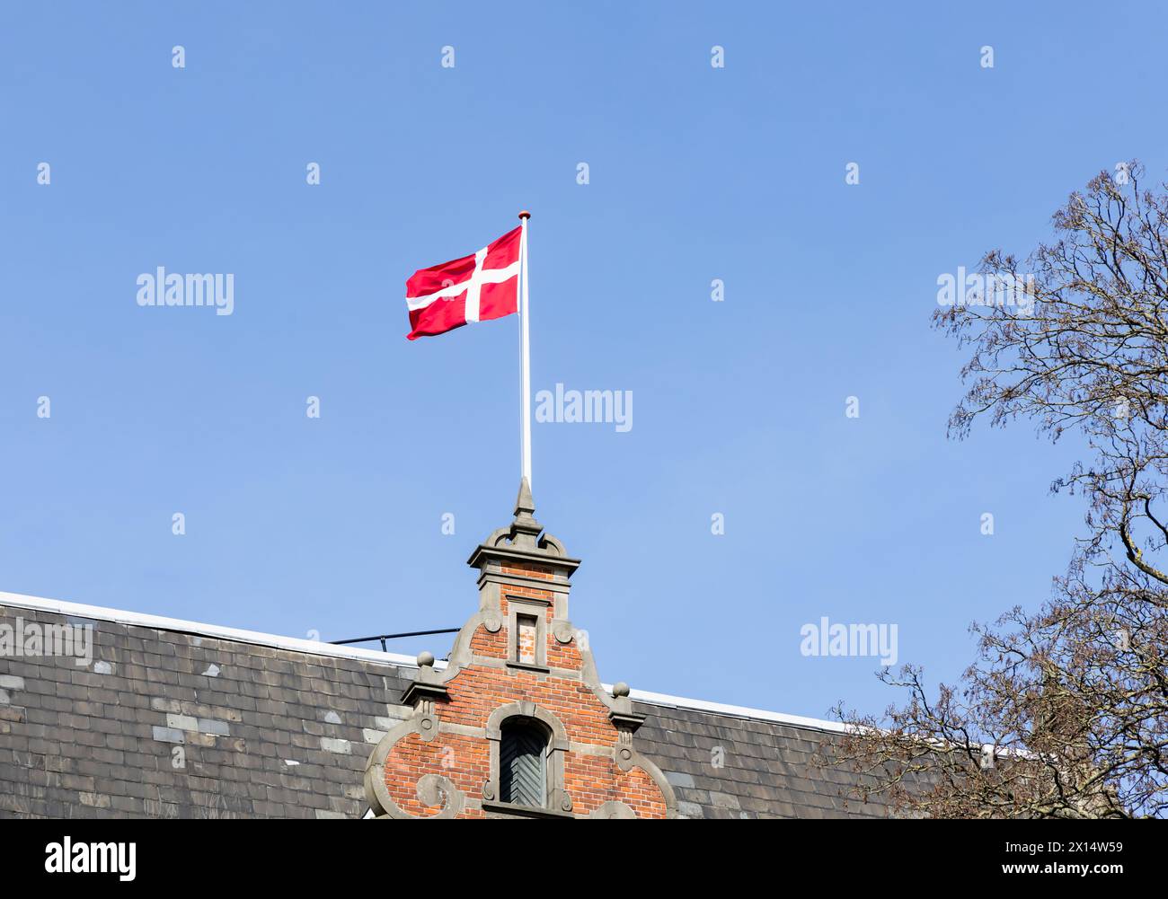 Danish flag on the roof of a building against a blue sky. Stock Photo