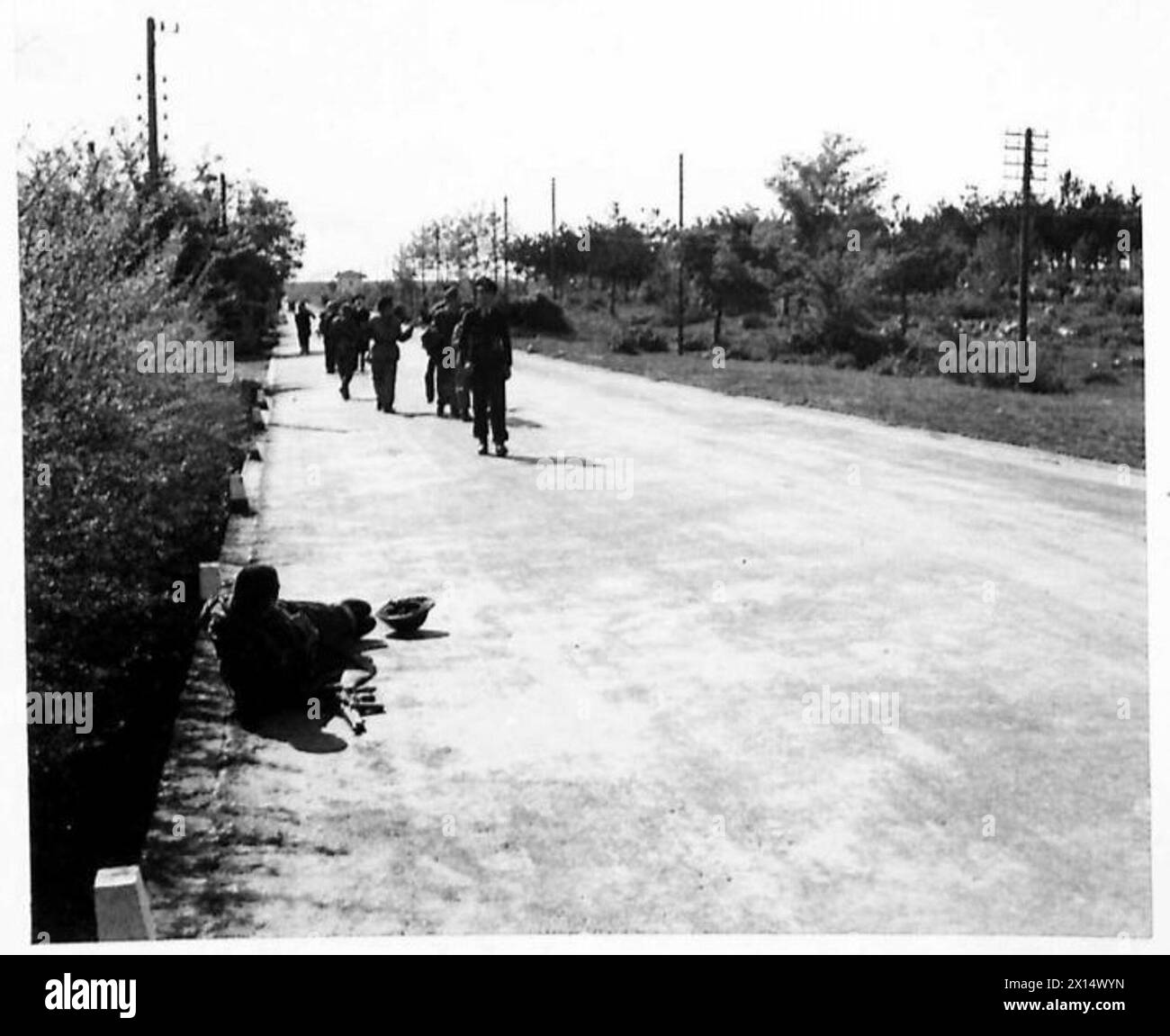 EIGHTH ARMY : ADVANCE TO TRIESTE - The Germans come along the road to give themselves up, bringing the three Naval officers with them. In the road, to the right, lies a New Zealander whose leg was broken when the Germans opened fire down the road. The Naval officers were:- Captain Dickenson (British), Senior Naval Officer, Northern Adriatic. Lieut. G.H. Foeller, U.S. Navy, attended staff of S.N.O., N.W. Mediterranean (who was badly wounded), Commander J. Kirstine, U.S. Coast Guard British Army Stock Photo