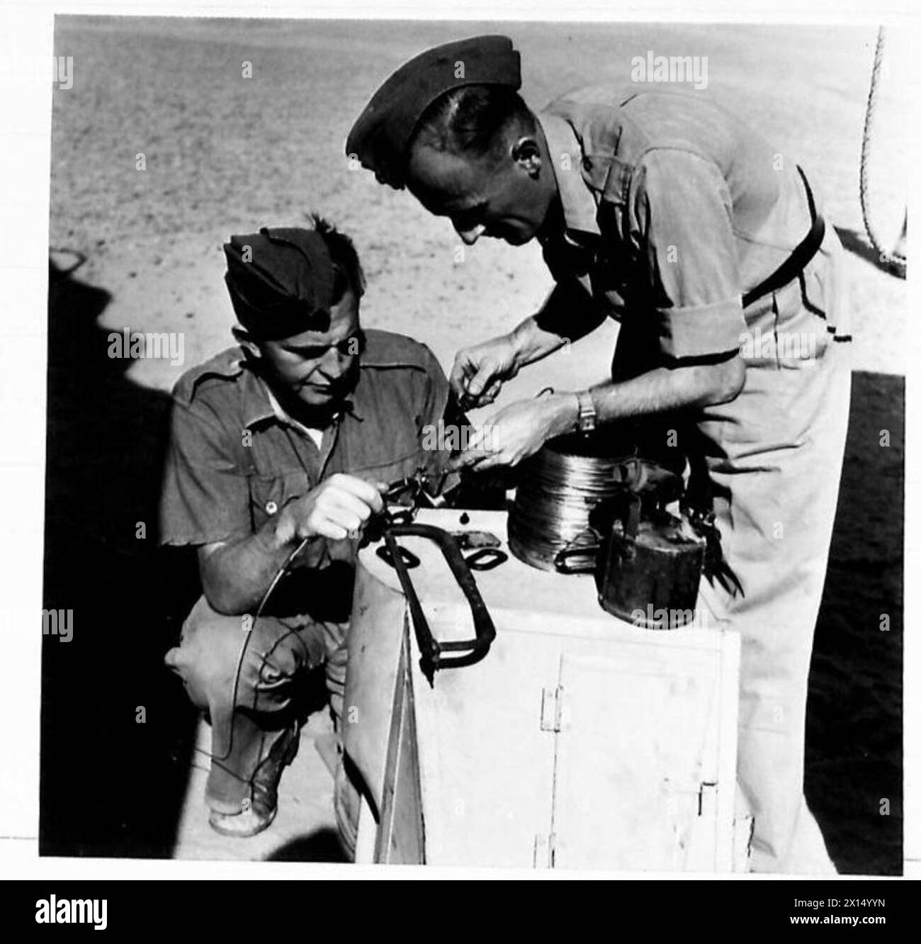 BRITISH EXPEDITIONARY FORCE TO FIGHT LOCUSTS IN THE MIDDLE EAST - Sig. Bourn (left) of Darlington solders an aerial together, assisted by Sig. Miller of Torquay United Nations Organisation [UNO] Stock Photo