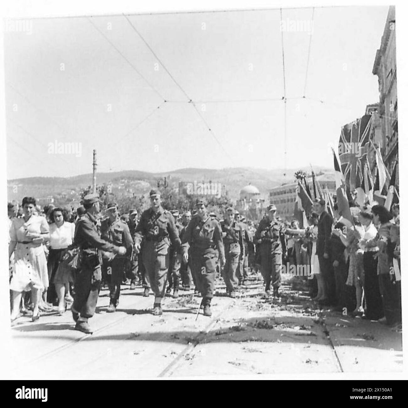 Spectators celebrate the liberation of Trieste by the Eighth Army, presenting flowers to troops as they march through the city. Stock Photo