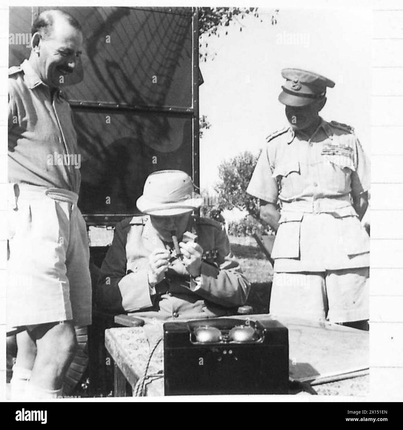 Prime Minister Winston Churchill discusses the battle situation with the Eighth Army while lighting a cigar. Stock Photo