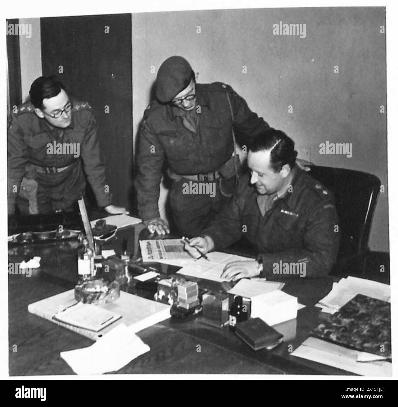 'REICHSENDER HAMBURG' NOW OPERATED BY THE BRITISH - Lieutenant Colonel P. Lieven, MC., of the Canadian Army, O.C. of No.4 Information Control Unit and head of the station, discusses programmed with his chief engineer Major Findley and Capt. C.R. Buxton his Radio Press Officer, at a conference British Army, 21st Army Group Stock Photo