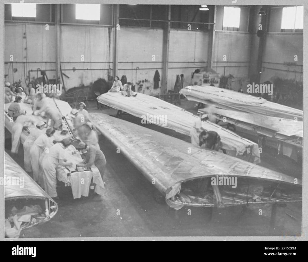 BRITAIN'S RECORD AIRCRAFT PRODUCTION ASSEMBLY OF 'WELLINGTON' BOMBERS - Stretching fabric on a wing Royal Air Force Stock Photo