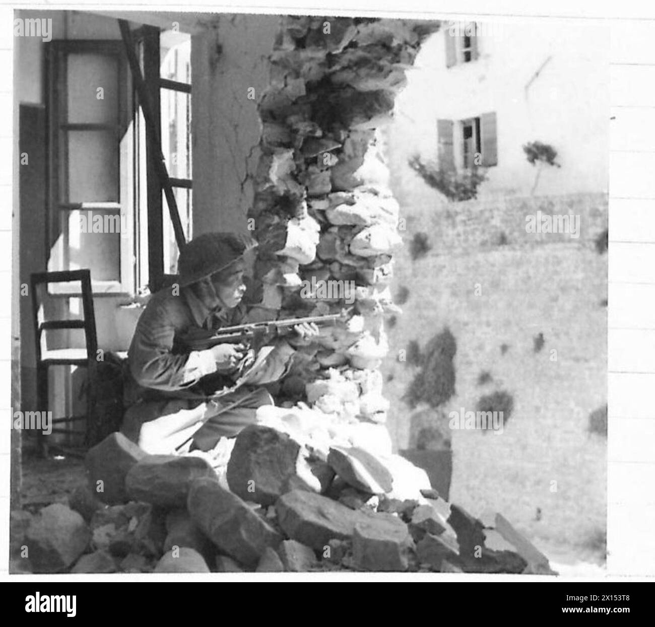 EIGHTH ARMY : CAPTURE OF TAVOLETO - A soldier, armed with a Tommy gun, takes up position in a wrecked house British Army Stock Photo