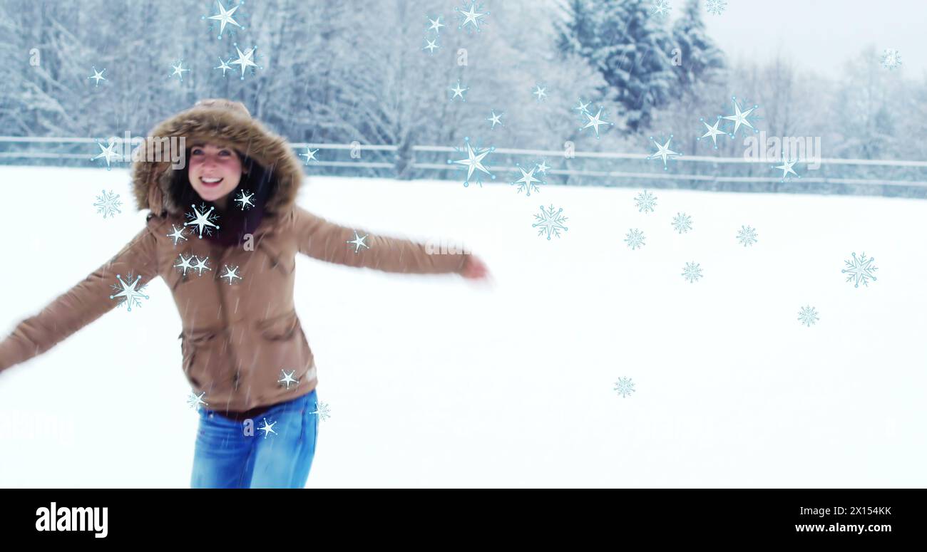 Image of snow falling over smiling caucasian woman dancing in snow Stock Photo