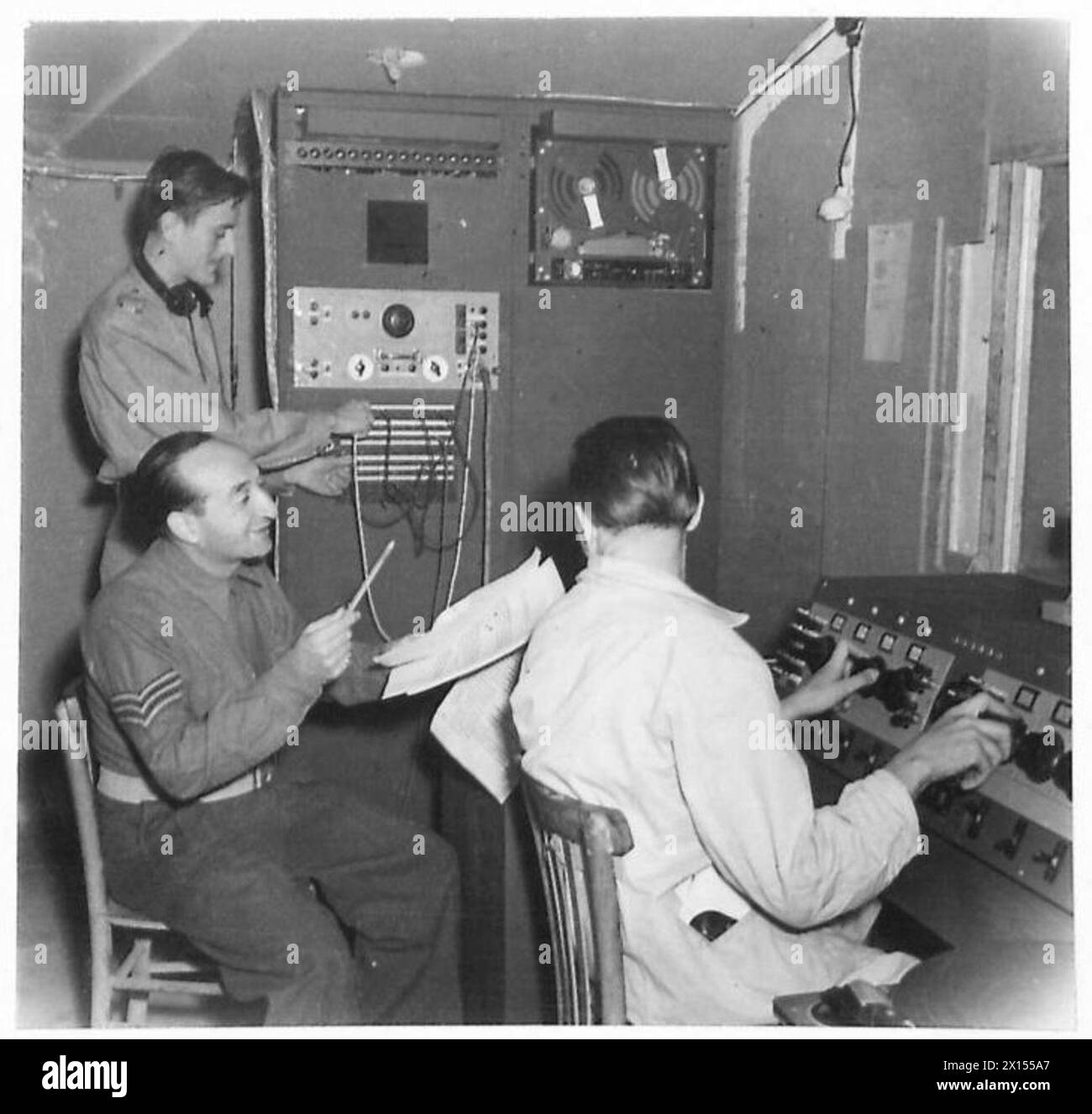 PWB BROADCASTING STATION AT KLAGENFURT - In the Control Room, British and German technicians work together. Here Mr. Stansfield of Thorngumbald Hall, near Hull is at the far switchboard, Sgt. Stoppler is announcing and Her Gorischnigg at switchboard British Army Stock Photo