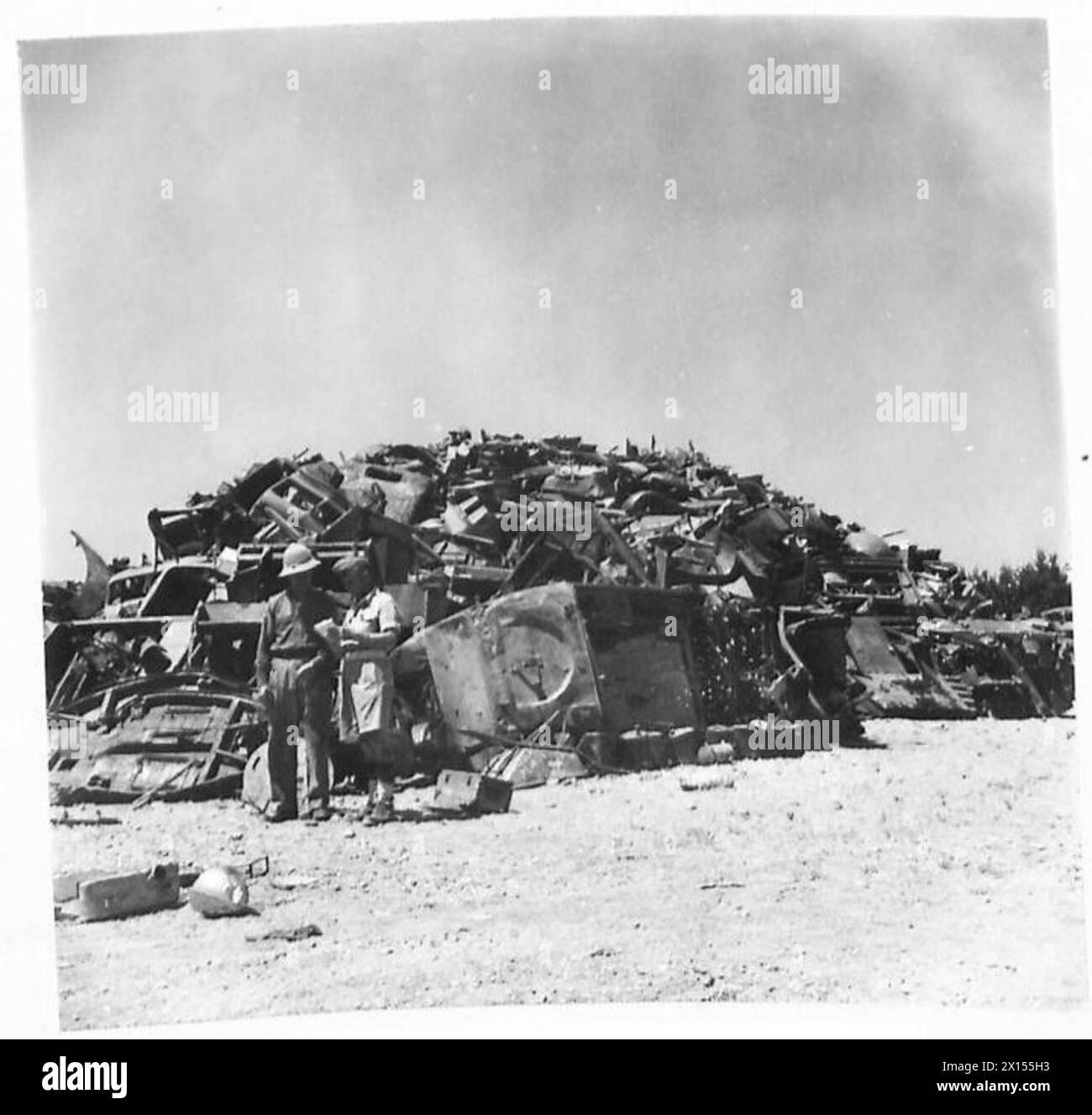 SALVAGE - A huge pile of scrap materials, with a sergeant cheking figures with a soldier British Army Stock Photo