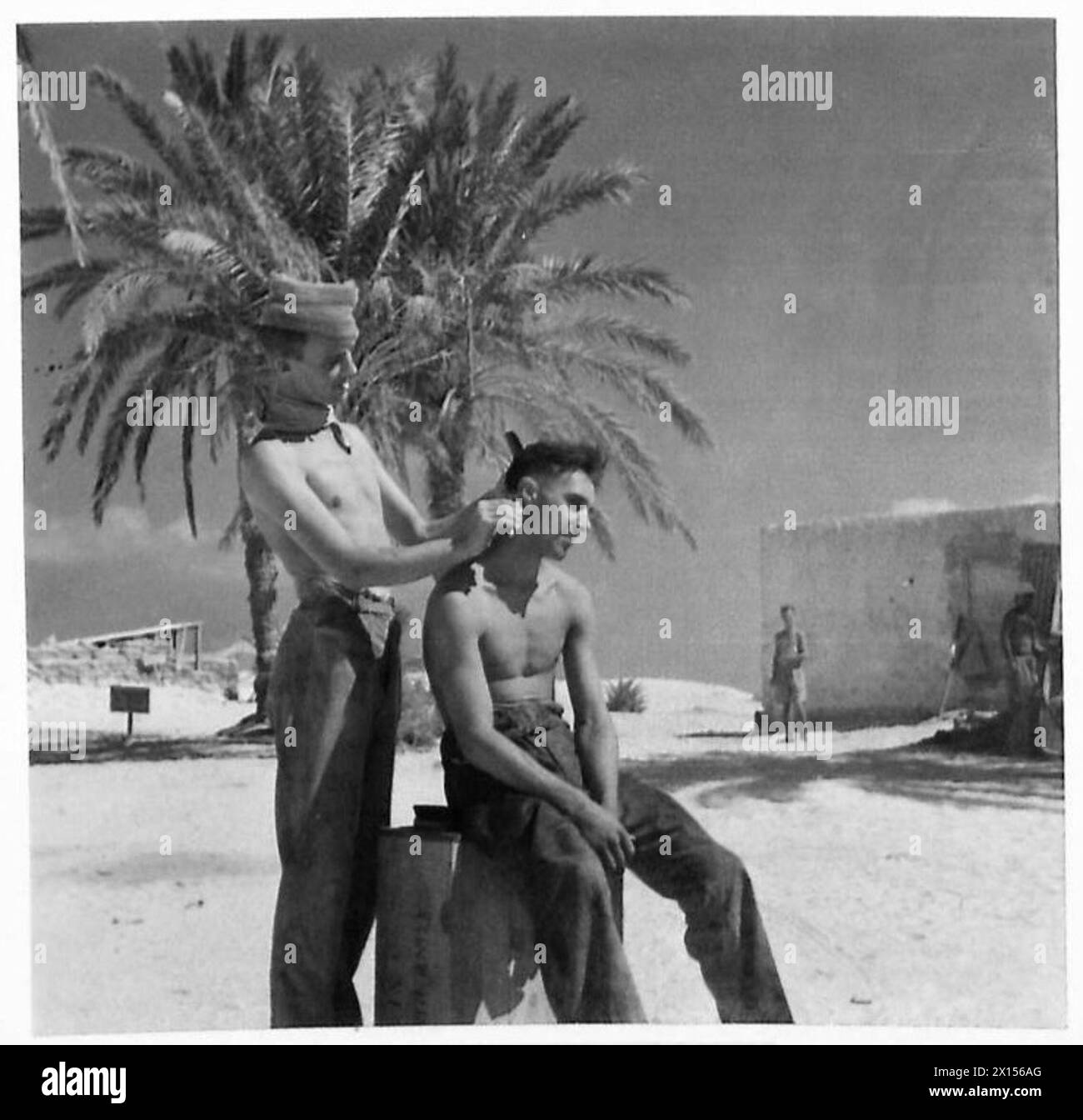 OFFICIAL PHOTOGRAPHS TAKEN IN THE WESTERN DESERT - An impromptu 'Barber's Shop' under the shadows of the palms British Army Stock Photo