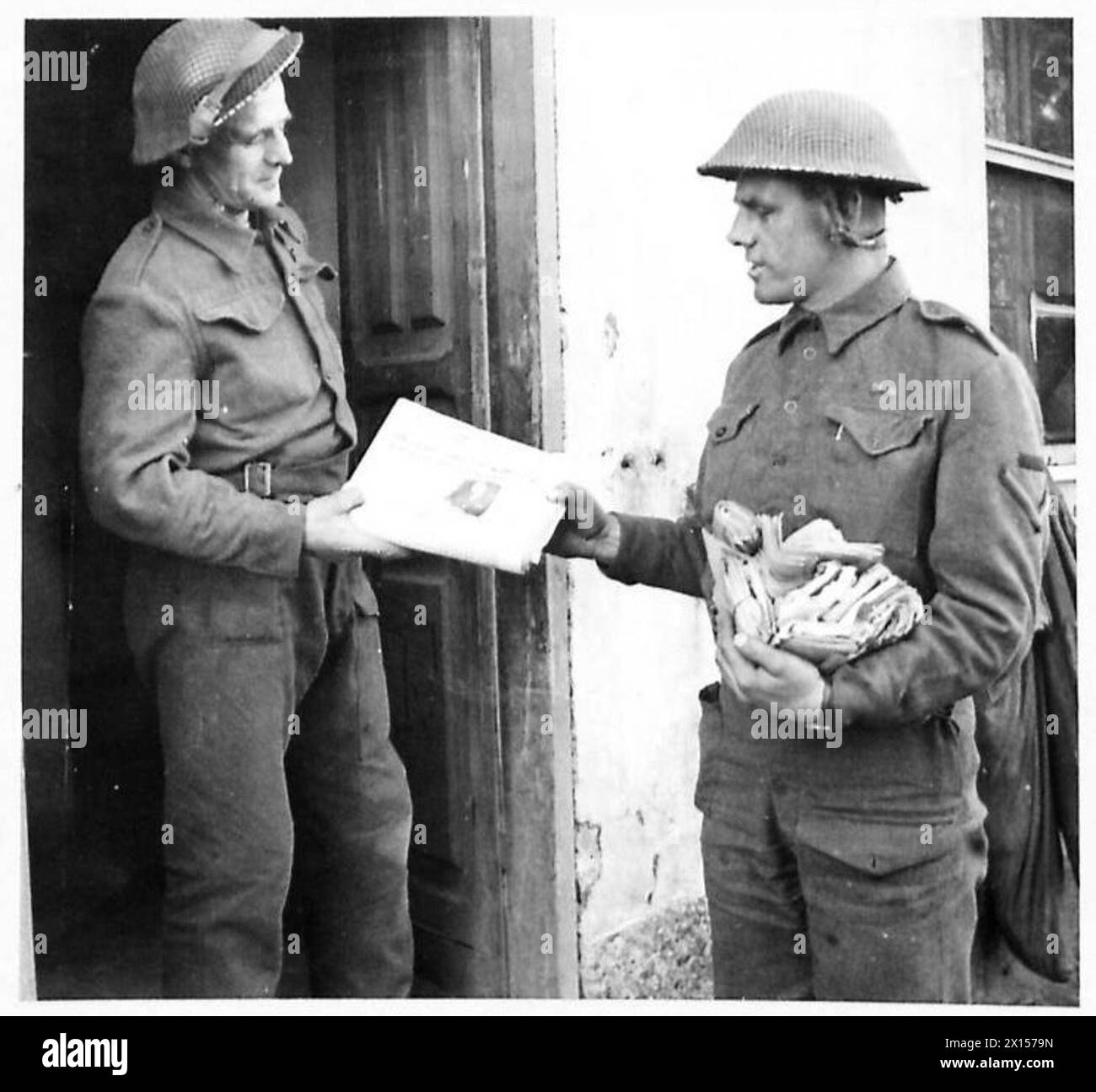 FIFTH ARMY : THE ARMY POST OFFICE IN THE ANZIO BRIDGEHEAD - Spr. A.R. Sheffers of 6, Osterly Street, Swansea, hands a Unit's quota of 'Union Jacks' to L/Cpl. S. Gordon of 26 Church Street, Dufftown, Banffshire. Spr. Sheffers has 26 years in the service of Swansea G.P.O. to his credit British Army Stock Photo