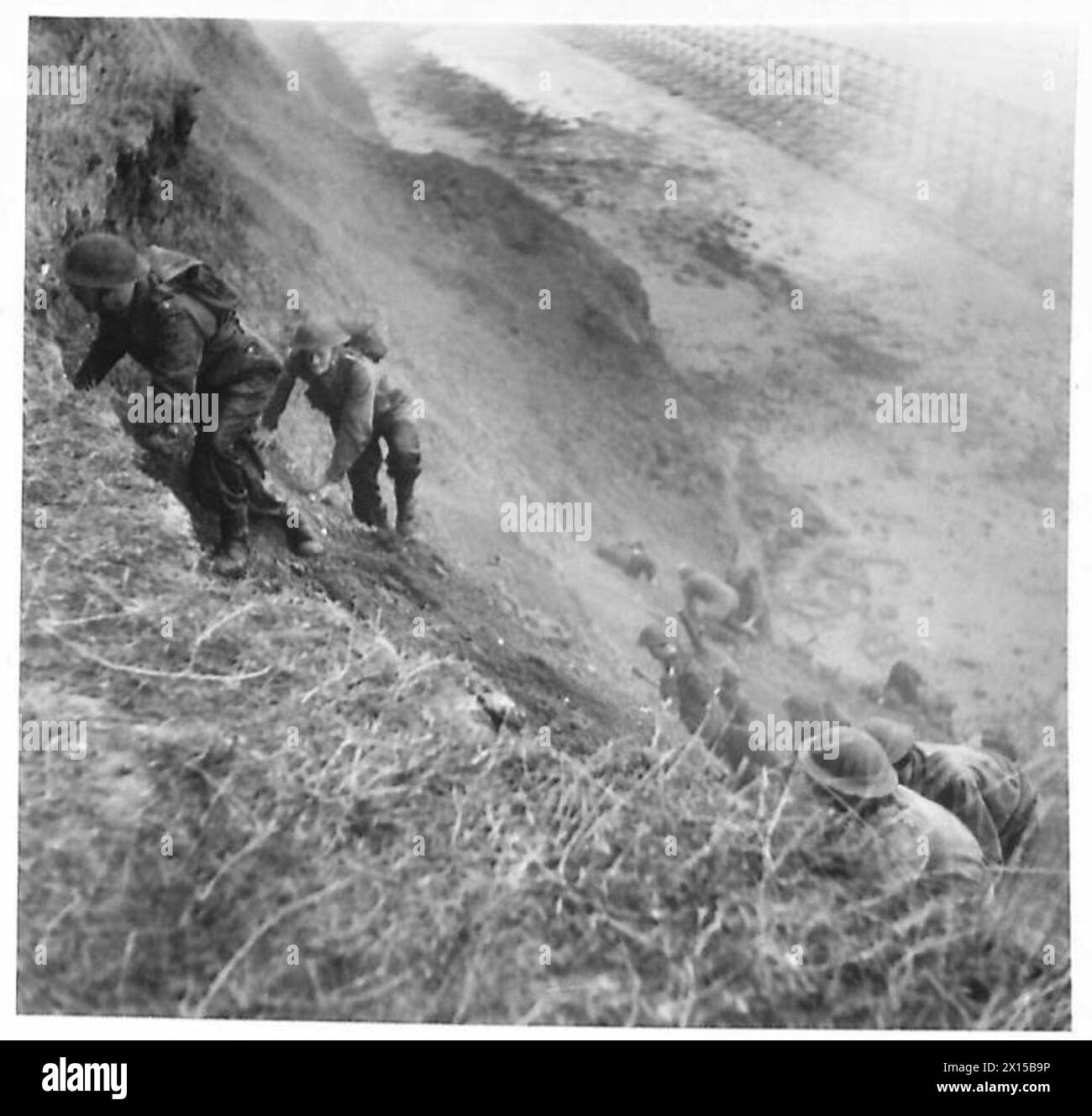 WAR CORRESPONDENTS VISIT BATTLE SCHOOL - The attacking party climb the cliff side ready to go into the attack British Army Stock Photo