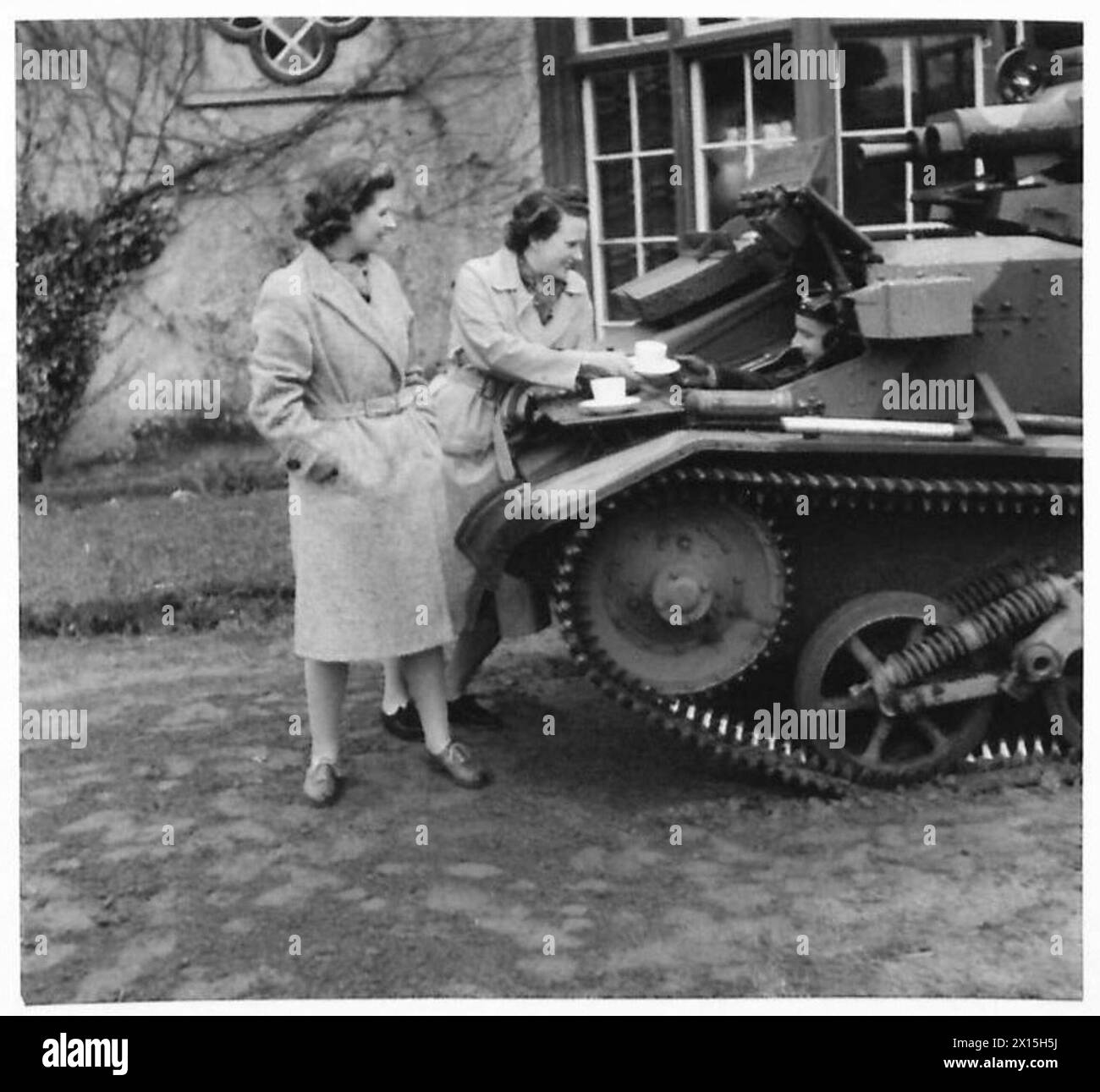 A WELCOME CUP O' TAY - Irish colleens giving a cup of tea to the crew of a light tank somewhere in Northern Ireland. The thatched house in the background is Deramore House, Bessbrook Co.Armagh, built in 1760. It was here that Isaac Corry, who built it, and Lord Castlereagh had their famous consultation and drafted the Act of Union, which was also signed in the House British Army Stock Photo