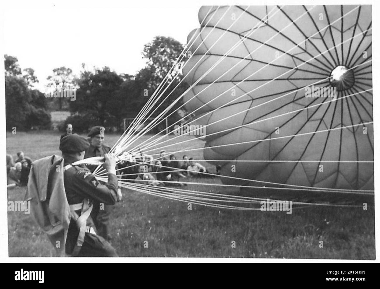 PARATROOPS DEMONSTRATE TO FACTORY WORKERS - Private Williamson, W. of Boldon Colliery, Co.Durham, demonstrates how the paratroop harness is fitted and the parachute opens Stock Photo