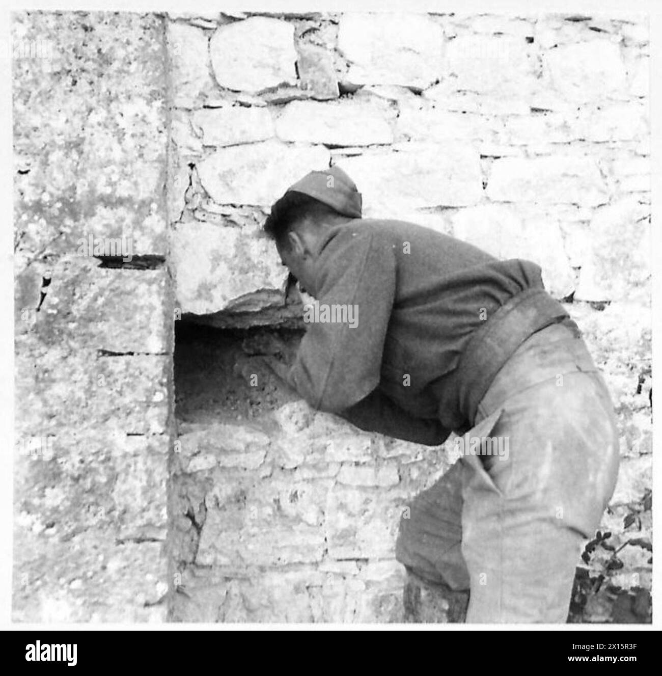 ITALY : EIGHTH ARMYWITH THE ROYAL ENGINEERSDEMOLITION FOR ROAD REPAIRS - Sapper Gibson of Glasgow tunnelling into a wall of ahouse about to be demolished for the debris to provide material for filling in the crater British Army Stock Photo