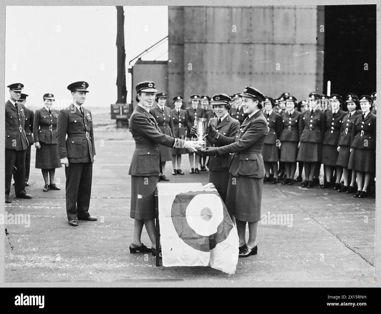 AIR COMMANDANT LADY WELSH TOURS R.A.F. STATIONS - Air Commandant Lady Welsh, Director of the W.A.A.F. recently visited stations of R.A.F. Bomber Command, and presented a cup to the most efficient W.A.A.F. sections in R.A.F. Bomber Command. The cup, known as the Sunderland Cup, was presented by the Mayor of Sunderland in memory of his son who was killed in service with Bomber Command. Every W.A.A.F. section in Bomber Command competed for the cup, which this year is shared by two sections. Picture (issued 1944) shows - Air Commandant Lady Welsh presenting the Sunderland Cup to Squadron Officer D Stock Photo