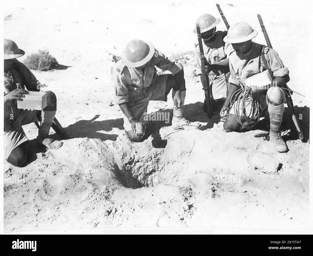 PHOTOGRAPHS OF AN INDIAN DIVISION IN THE WESTERN DESERT - Miners and Sappers of an Indian Division exploding an Italian bomb that failed to explode when dropped. Gelignite was placed next to the bomb and the bomb exploded British Army Stock Photo