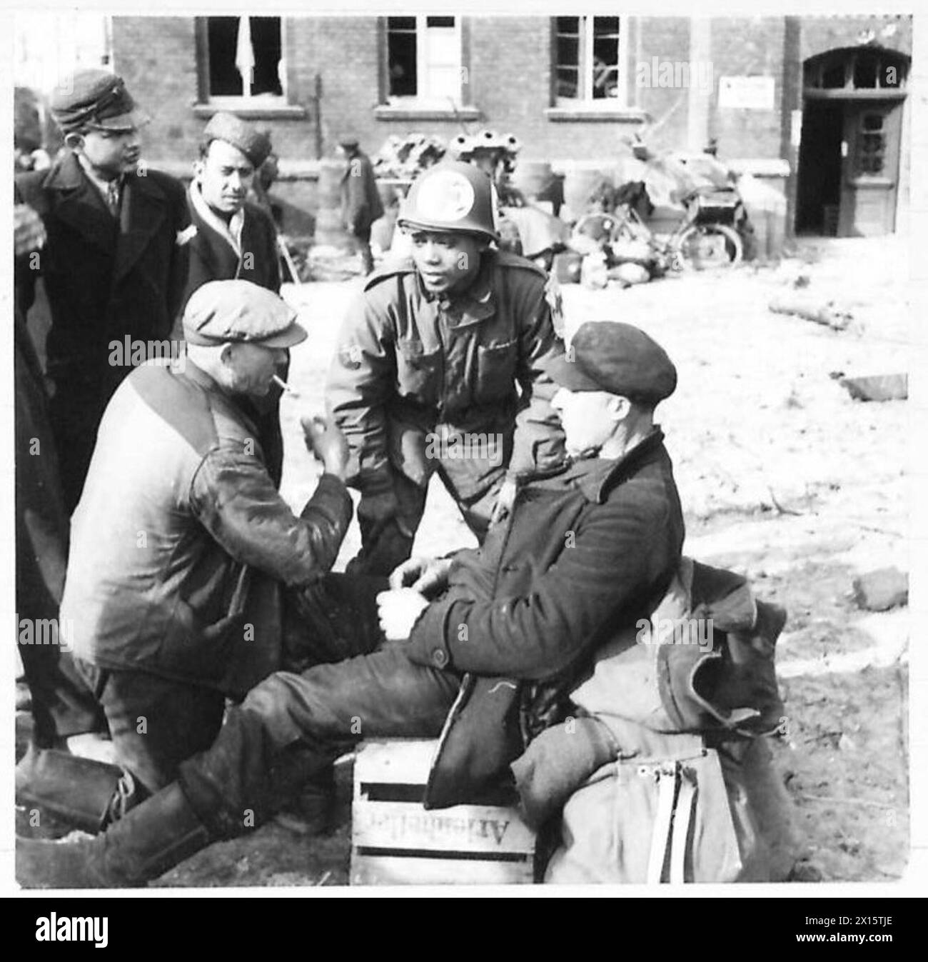 THE DISPLACED PERSONS AND REFUGEES IN GERMANY - Corporal Frank Gaskins of the US Medical Corps (in private life from Washington) in conversation with Russian and Polish forced labourers. Some 300 displaced persons, Poles, Russians, Italians, French and Dutch, who were doing forced labour in Germany, are being fed by the 516th Department of the Military Government in the ruined town of Wesel American Army Stock Photo