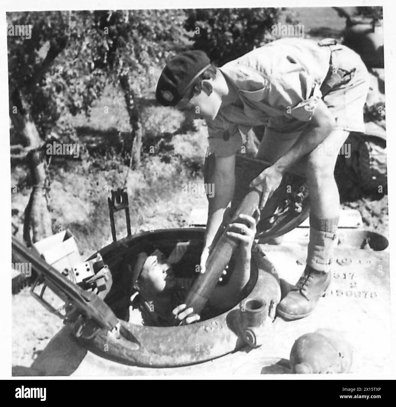 EIGHTH ARMY : CANADIAN TANKMEN PREPARE FOR ACTION - Tpr. C.H. Bookholt of Halifax, Canada, hands shells to Tpr. Pichette of Ontario, for stowing in the magazine of the tank British Army Stock Photo