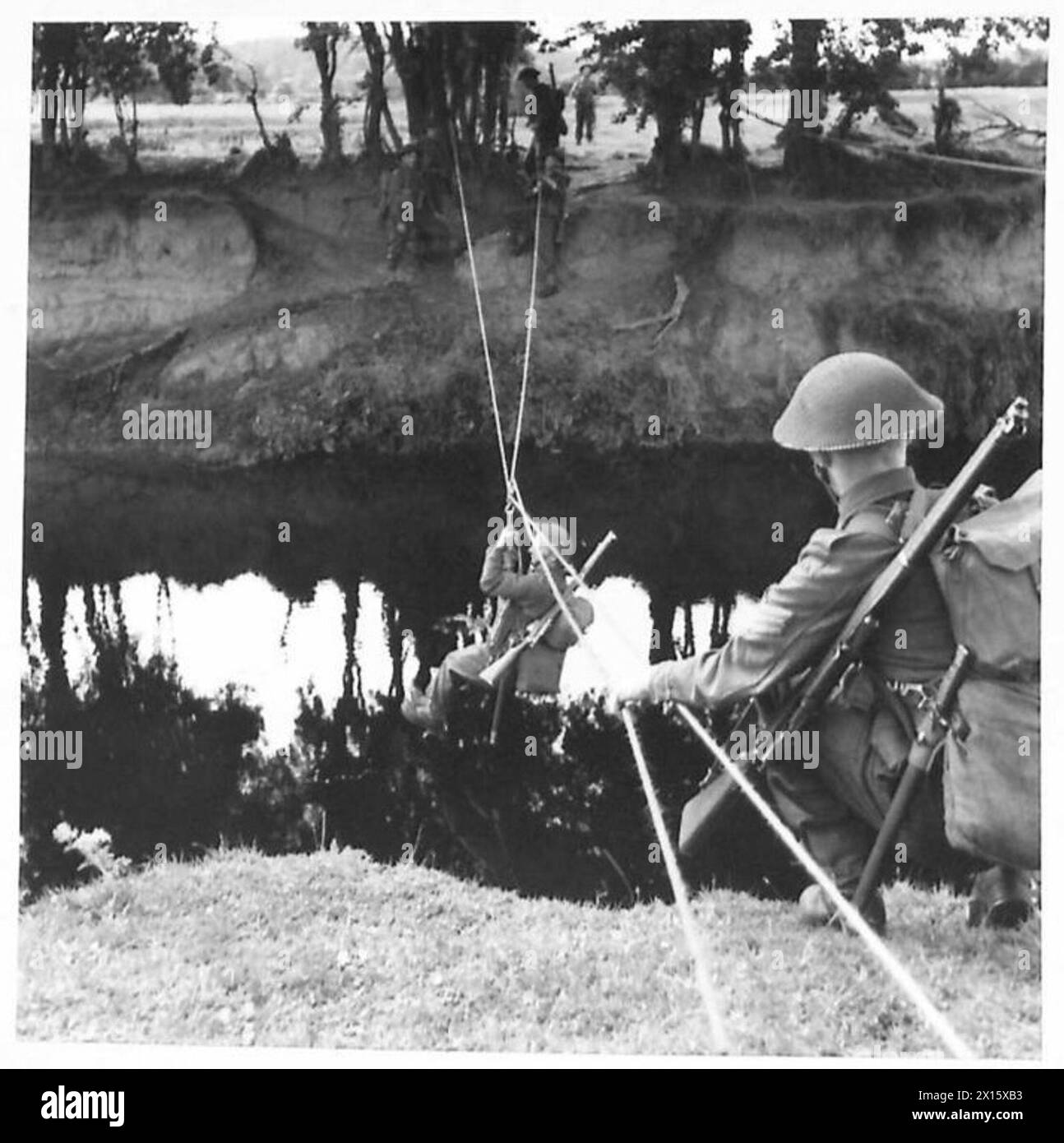 GETTING ACROSS A RIVER - A pick axe suspended from the pulley makes a first class seat on which to be hauled across the river British Army Stock Photo