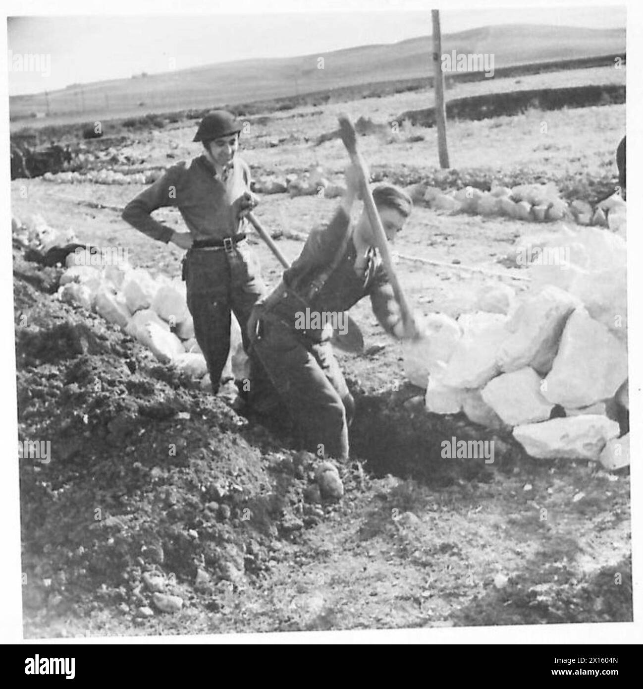 THE BRITISH ARMY IN THE TUNISIA CAMPAIGN, NOVEMBER 1942-MAY 1943 - Engineers of the 1256th Field Company RE digging trenches at each side of the road near Beja, 29 December 1942. These are filled with large stones to form a foundation. Supply lines are an obvious essential in any large scale attack and the use of the roads is imperative for the transport of munitions and supplies to the front.The roads in forward area were mainly bad and since the majority of transport had to move by night without lights, the maintenance of supplies was a tedious and difficult task.Many key points, particularl Stock Photo